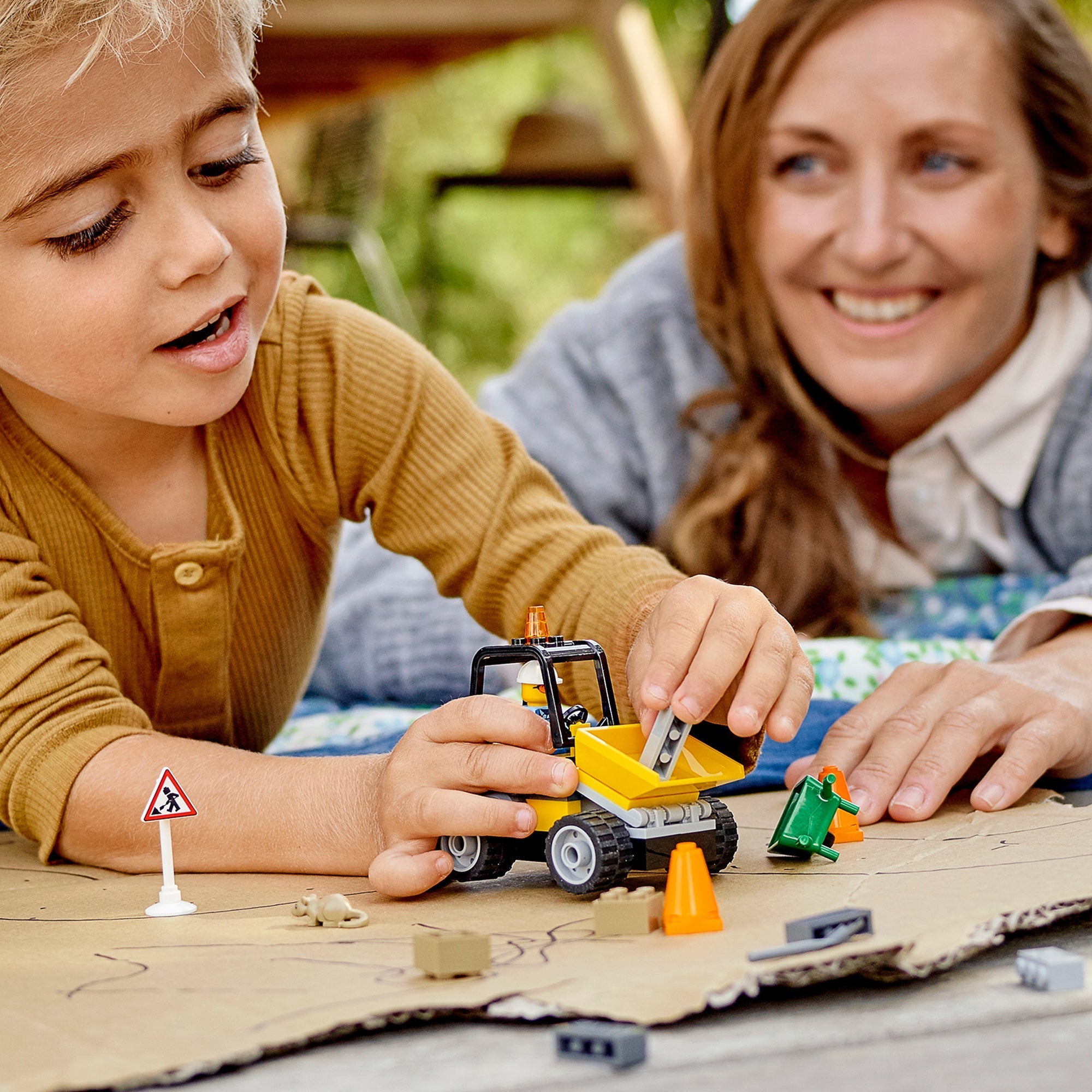 Child playing with LEGO® City Roadwork Truck toy, engaged in creative road construction activities.
