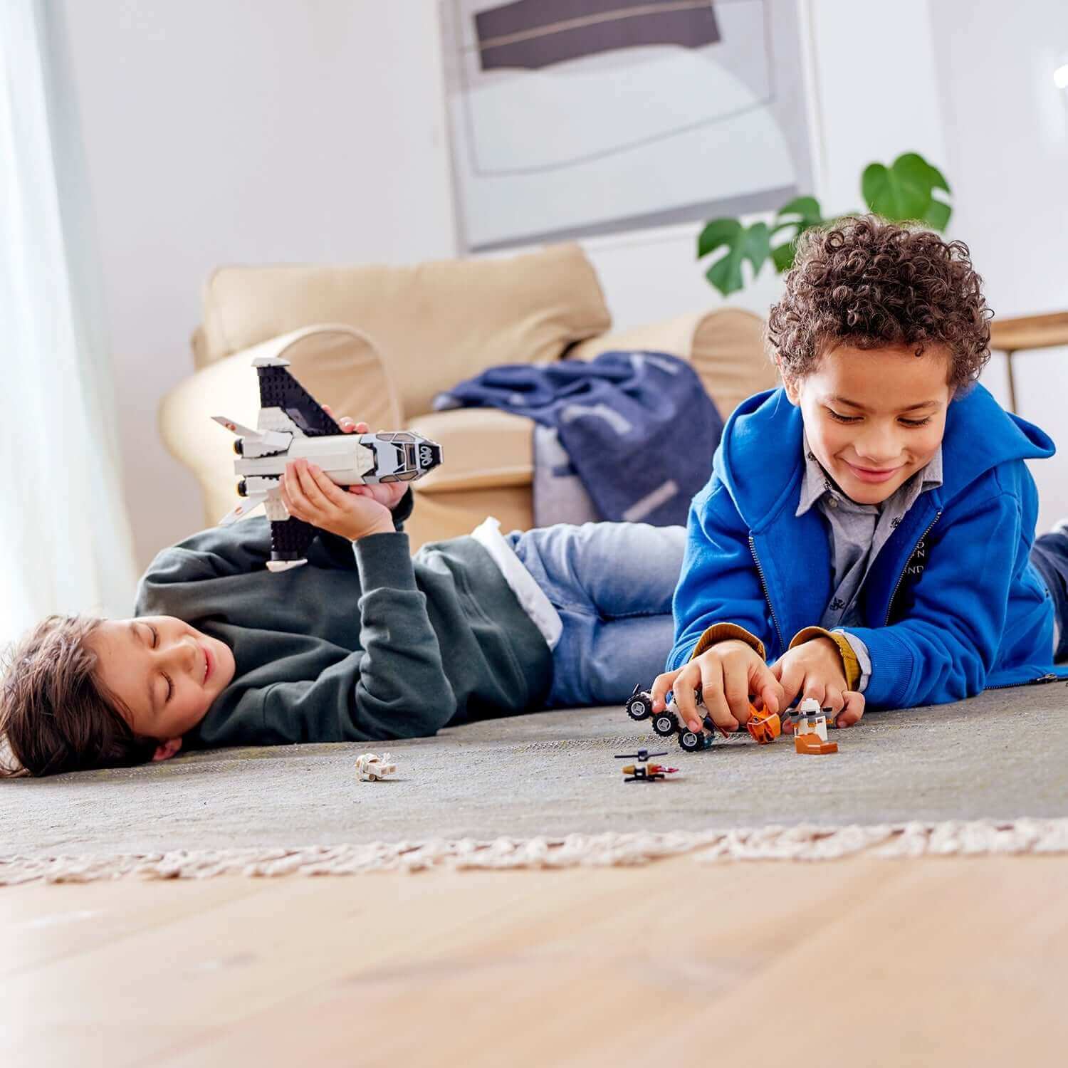 Two children playing with LEGO® City Mars Research Shuttle and space toys on a cozy rug indoors.