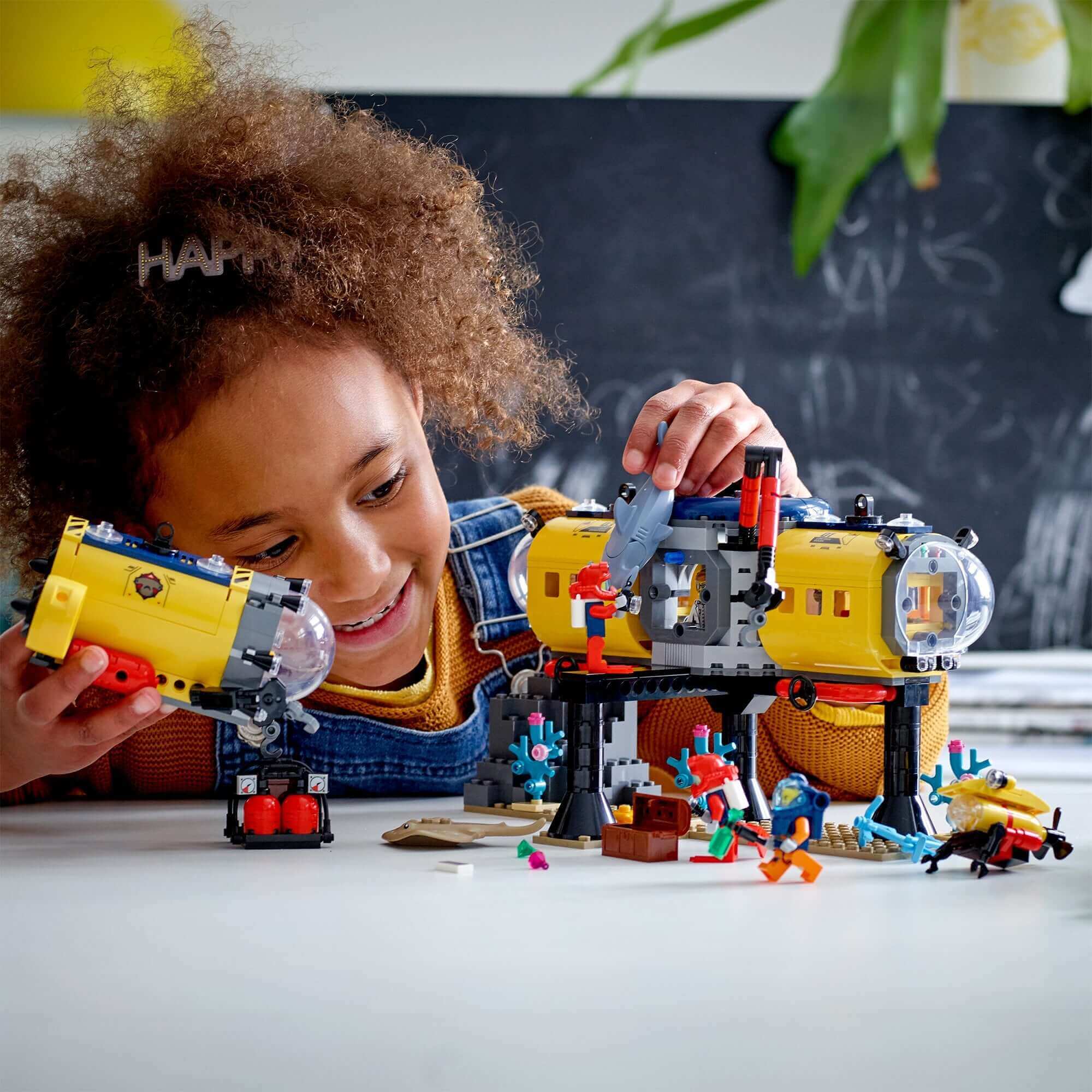 Child exploring LEGO® City Ocean Exploration Base deep sea set 60265 with submarines and underwater creatures.