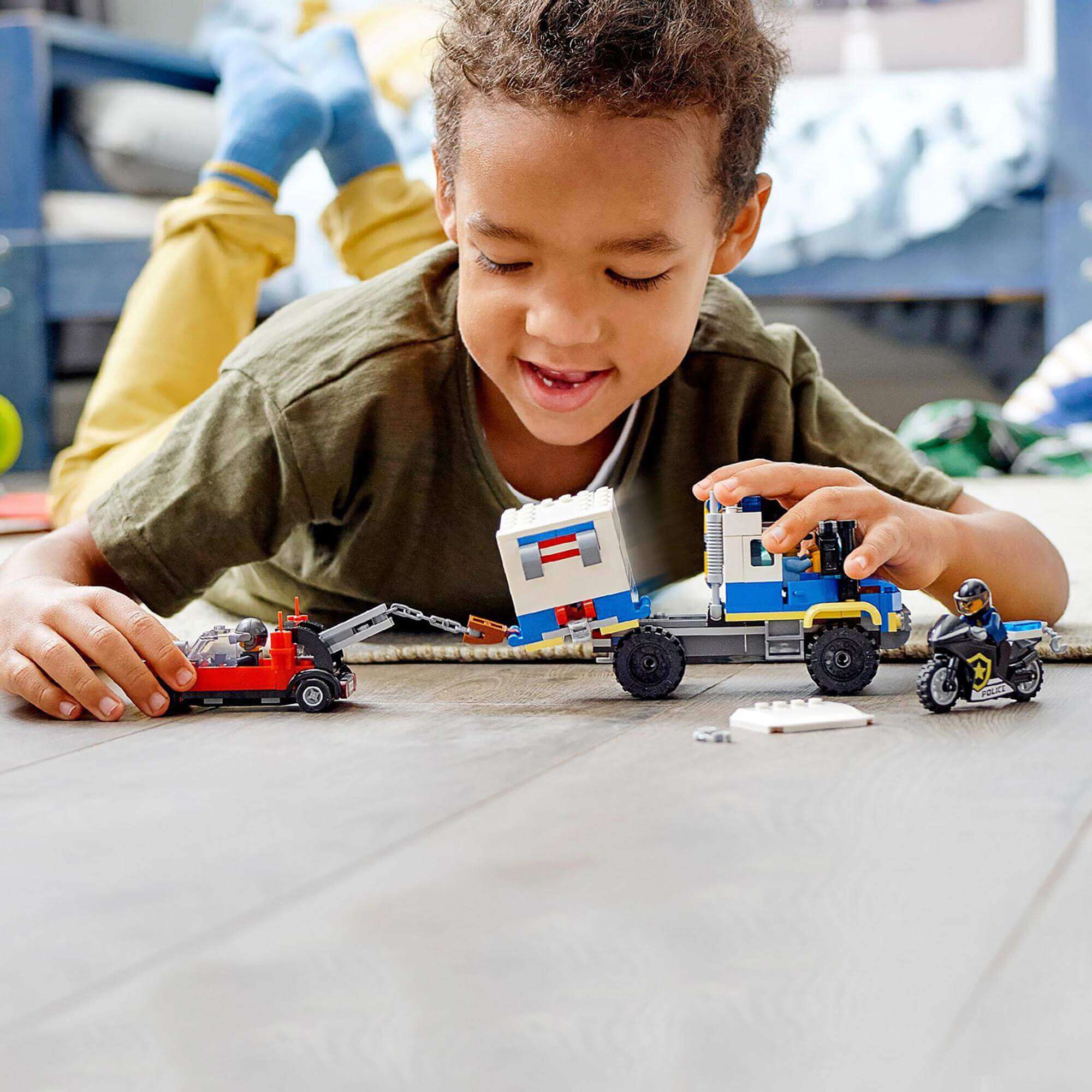 Child playing with LEGO City Police Prisoner Transport Truck toy, engaging in imaginative play with vehicles.
