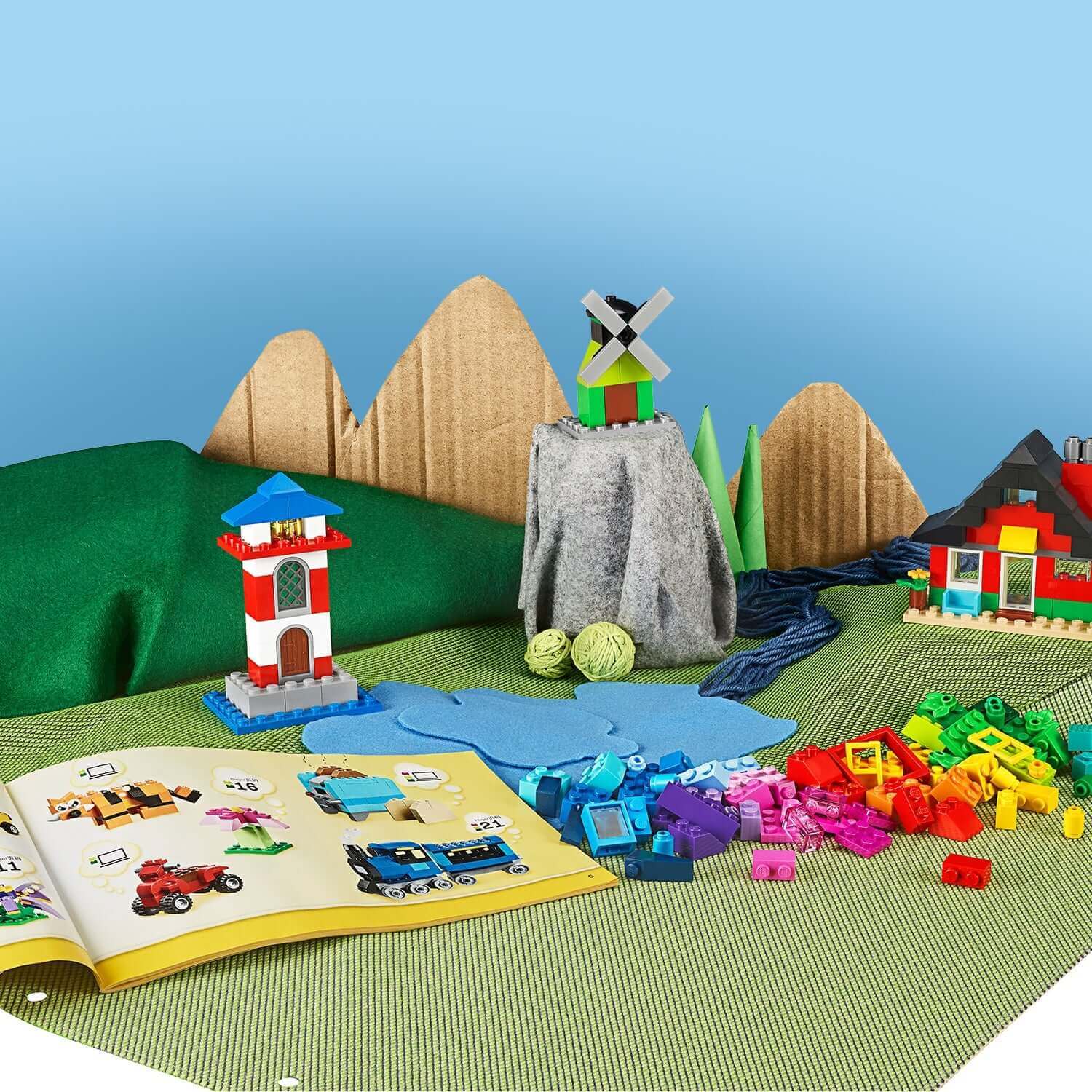 Colorful LEGO® Classic 4+ Bricks and Houses Set 11008 with built structures and instruction book on a playful landscape.