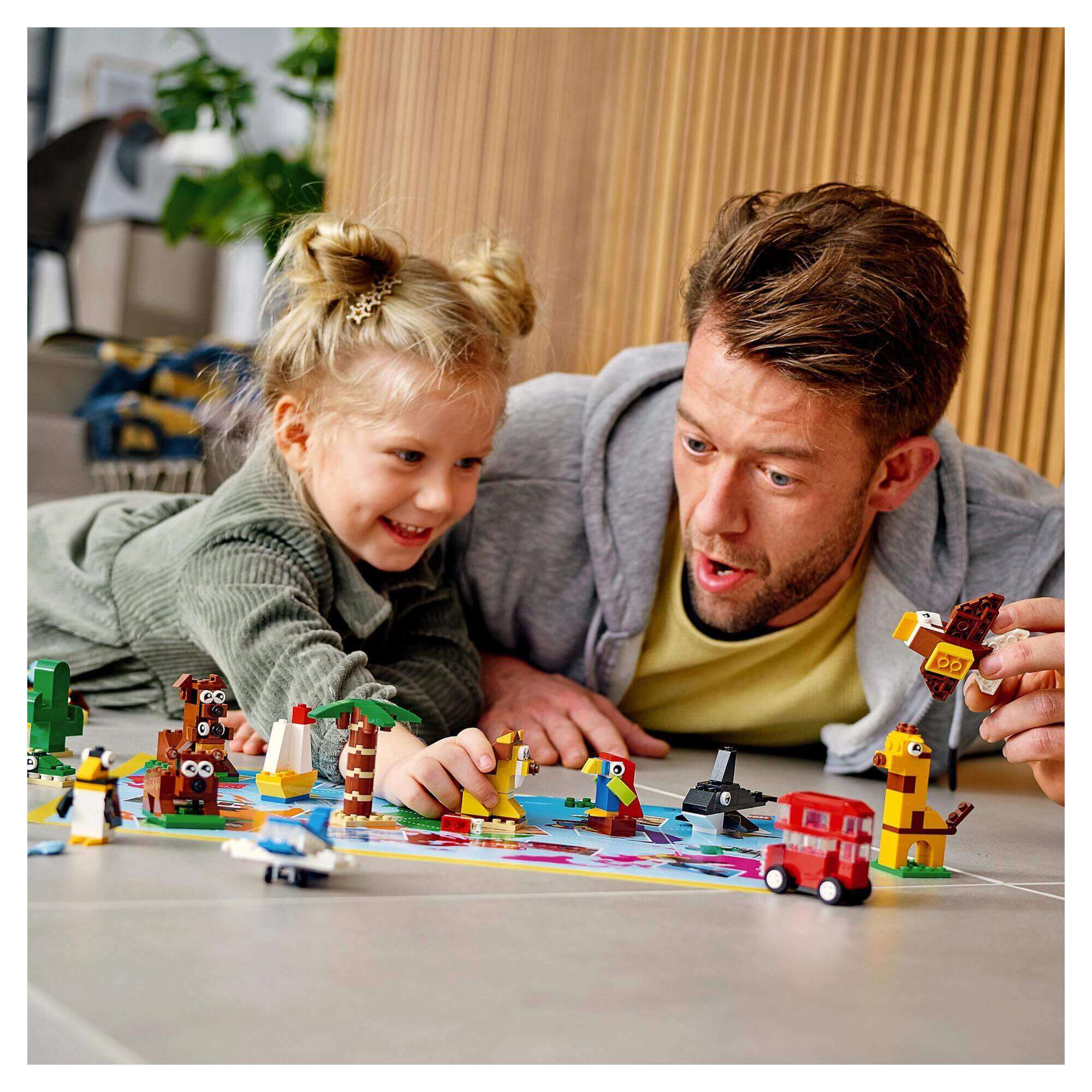 Father and child playing with LEGO® Classic Around the World Bricks Set 11015, surrounded by unique animal and object builds.