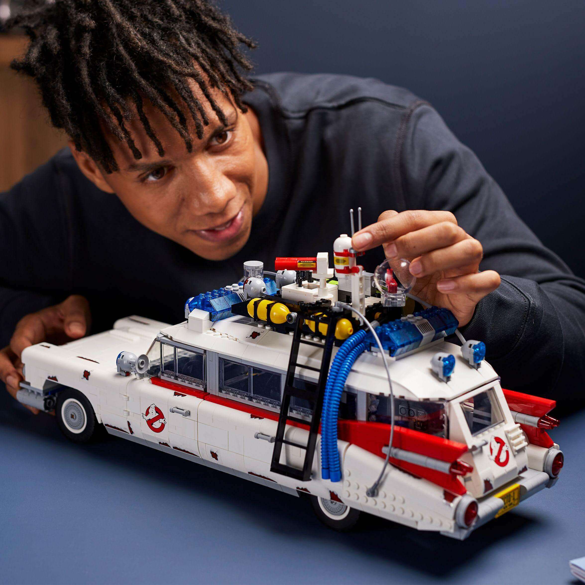 Person assembling LEGO® Creator Expert Ghostbusters ECTO-1 model, showcasing details and creativity.
