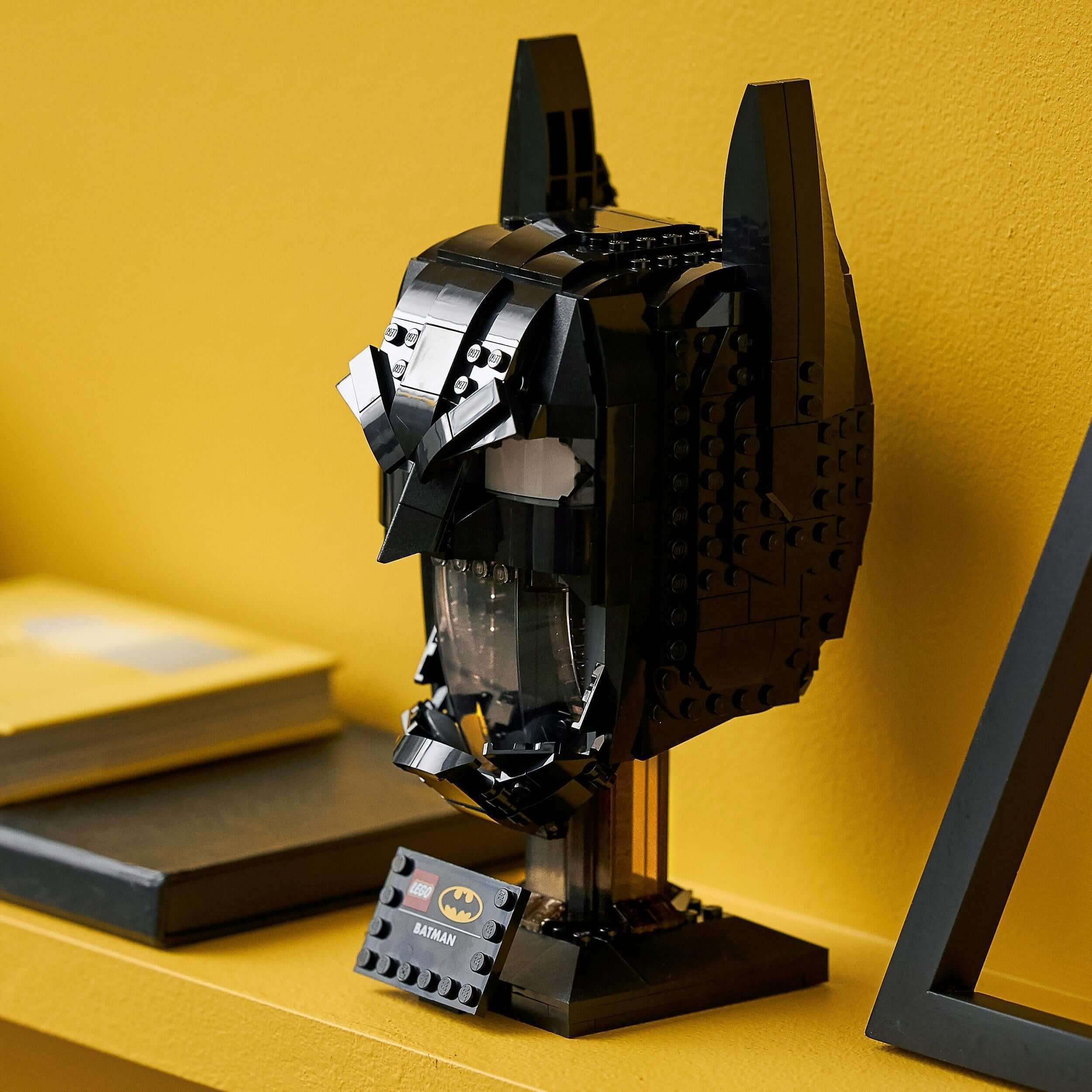 LEGO® DC Batman Cowl Set 76182 for adults displayed on a shelf against a yellow background.
