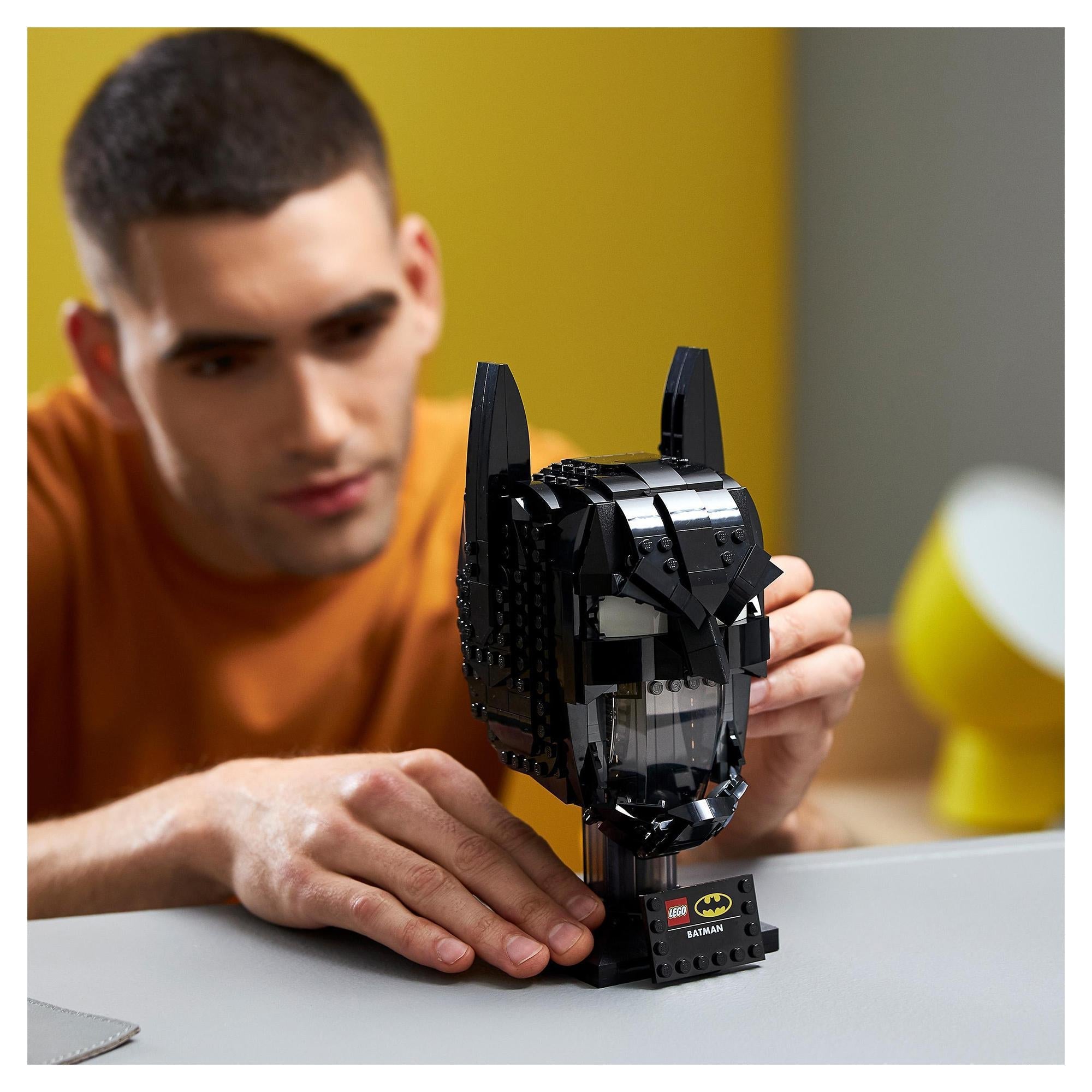 Adult assembling LEGO® DC Batman Cowl Set 76182, showcasing a detailed Batman cowl replica.