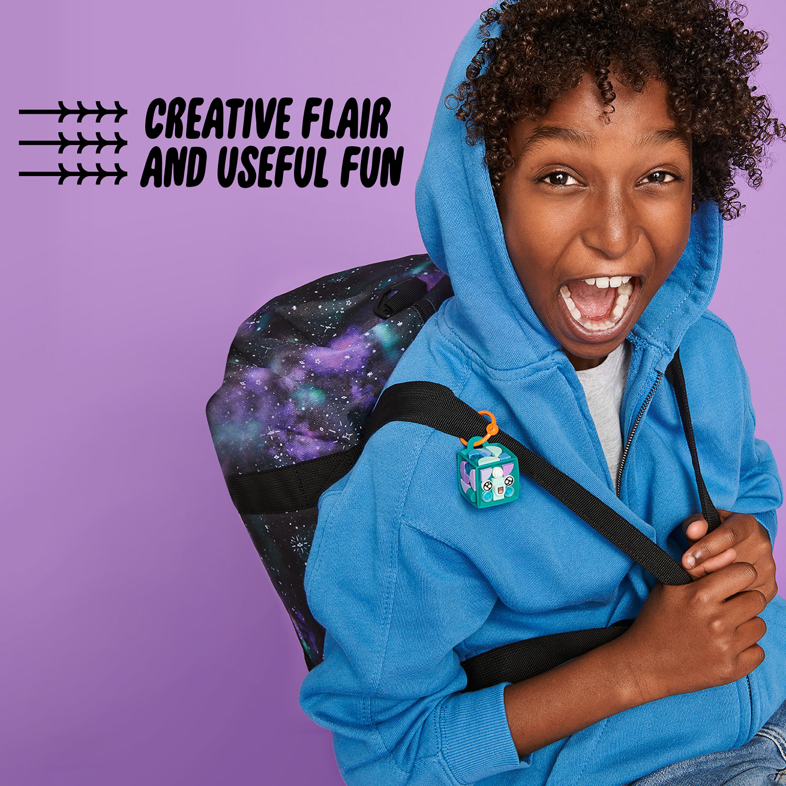 Child wearing blue hoodie with LEGO® DOTS narwhal bag tag on backpack, showcasing creativity and fun.