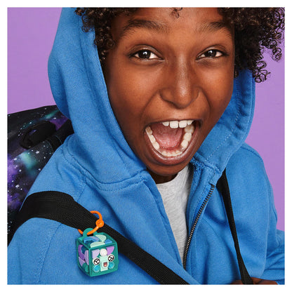 Child smiling excitedly with LEGO DOTS Narwhal Bag Tag on backpack, showcasing customizable accessories.