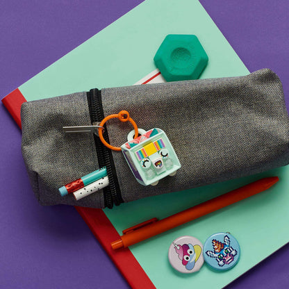 LEGO® DOTS Unicorn Bag Tag kit on a pencil case, surrounded by pens and colorful tiles for creative crafting.
