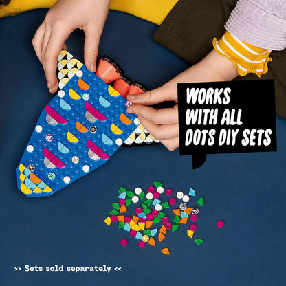 Child crafting with LEGO® DOTS tiles, showcasing a colorful design and additional tiles for creative projects.