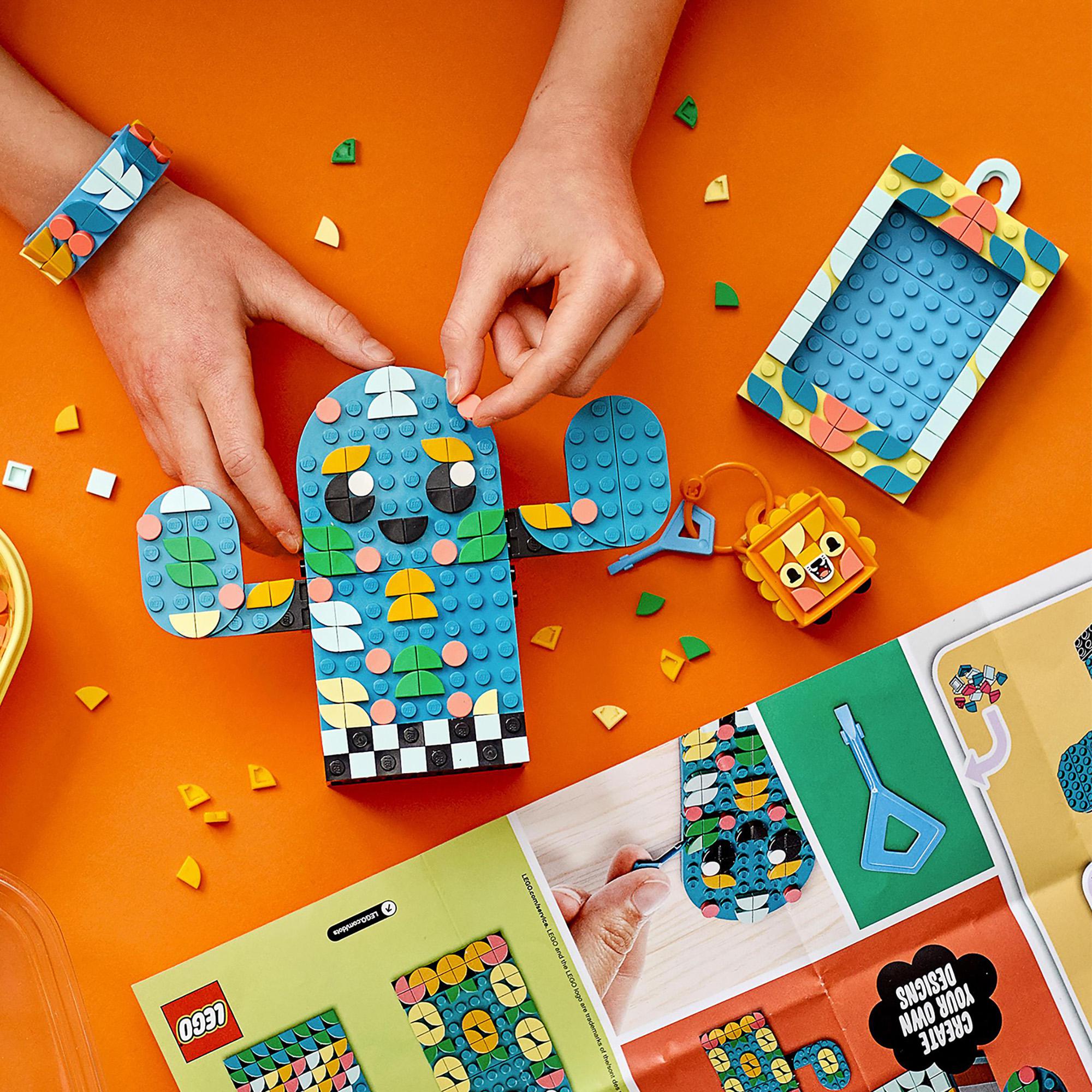 Child assembling colorful LEGO® DOTS crafts including a bracelet, character, and picture frame on a vibrant orange background.