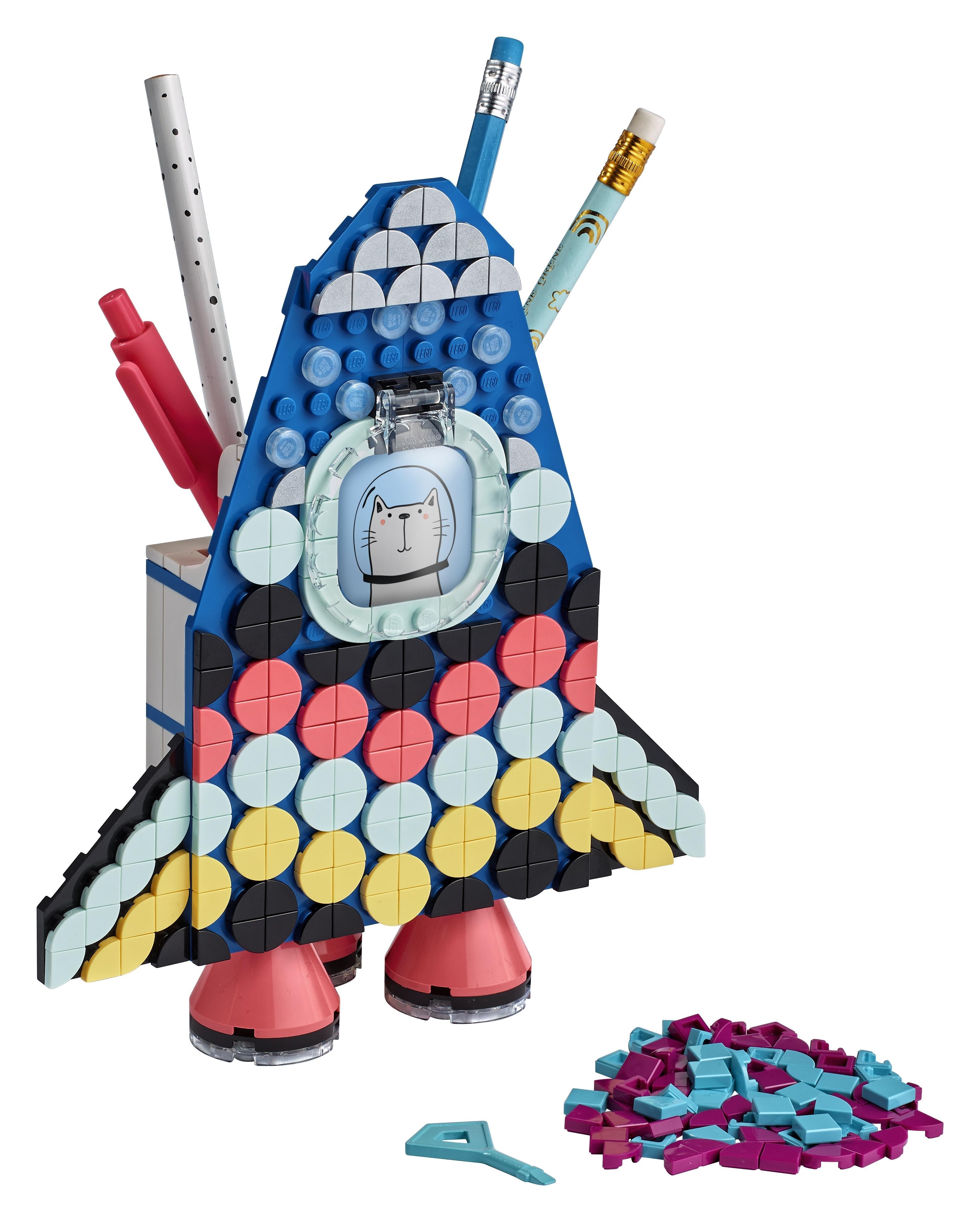 Colorful LEGO® DOTS Pencil Holder Craft Set shaped like a rocket, featuring various pens and vibrant tiles for creativity.