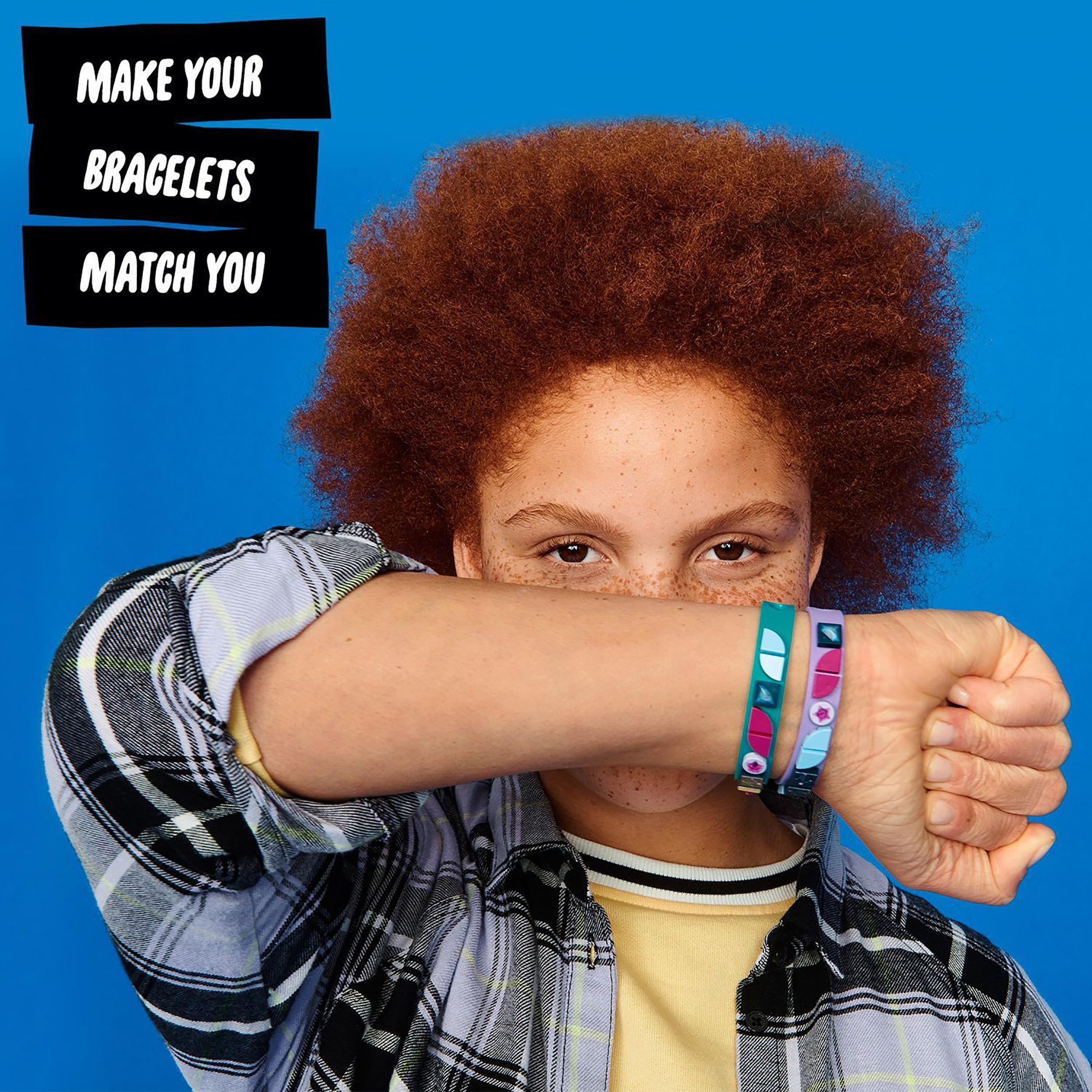 Child showing LEGO® DOTS Starlight Bracelets on wrist, featuring colorful tiles against a blue background.