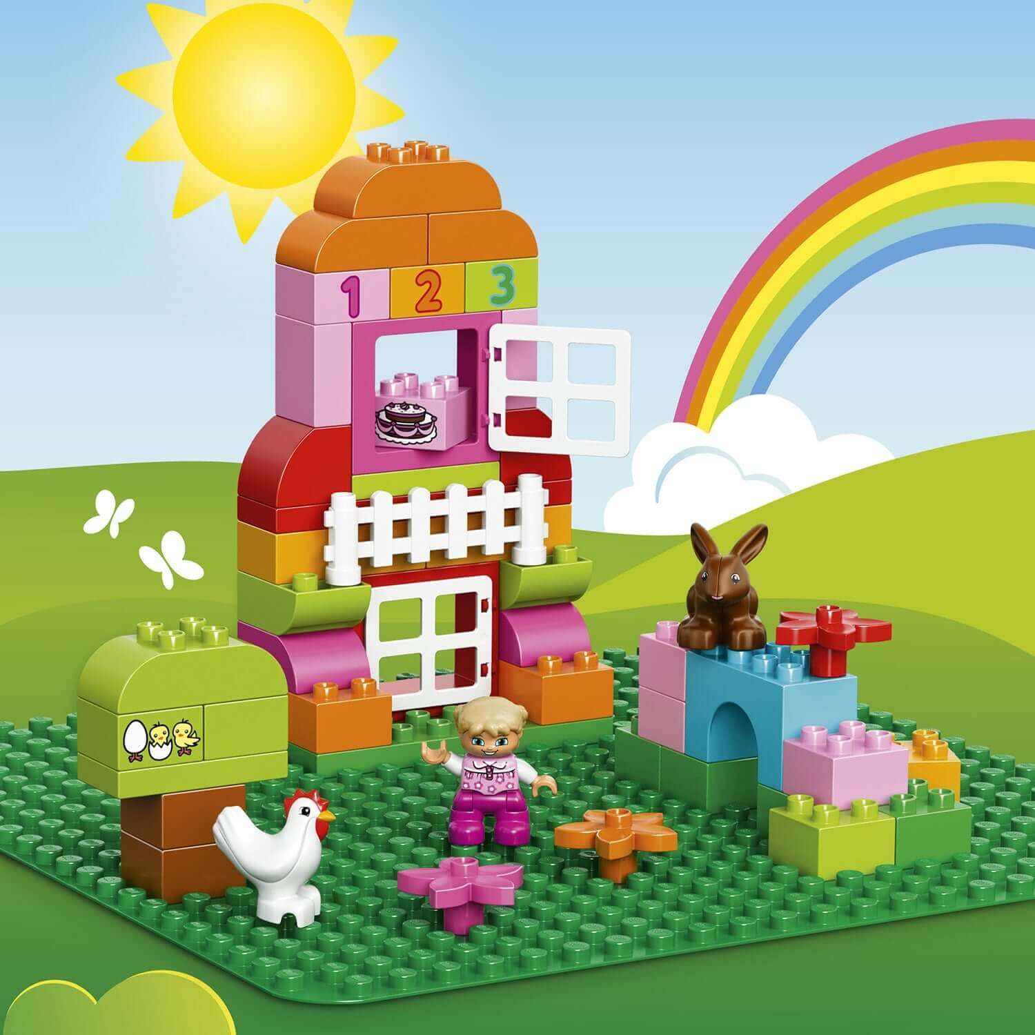 Colorful LEGO DUPLO building with figures and animals on a green base plate under a sunny sky.