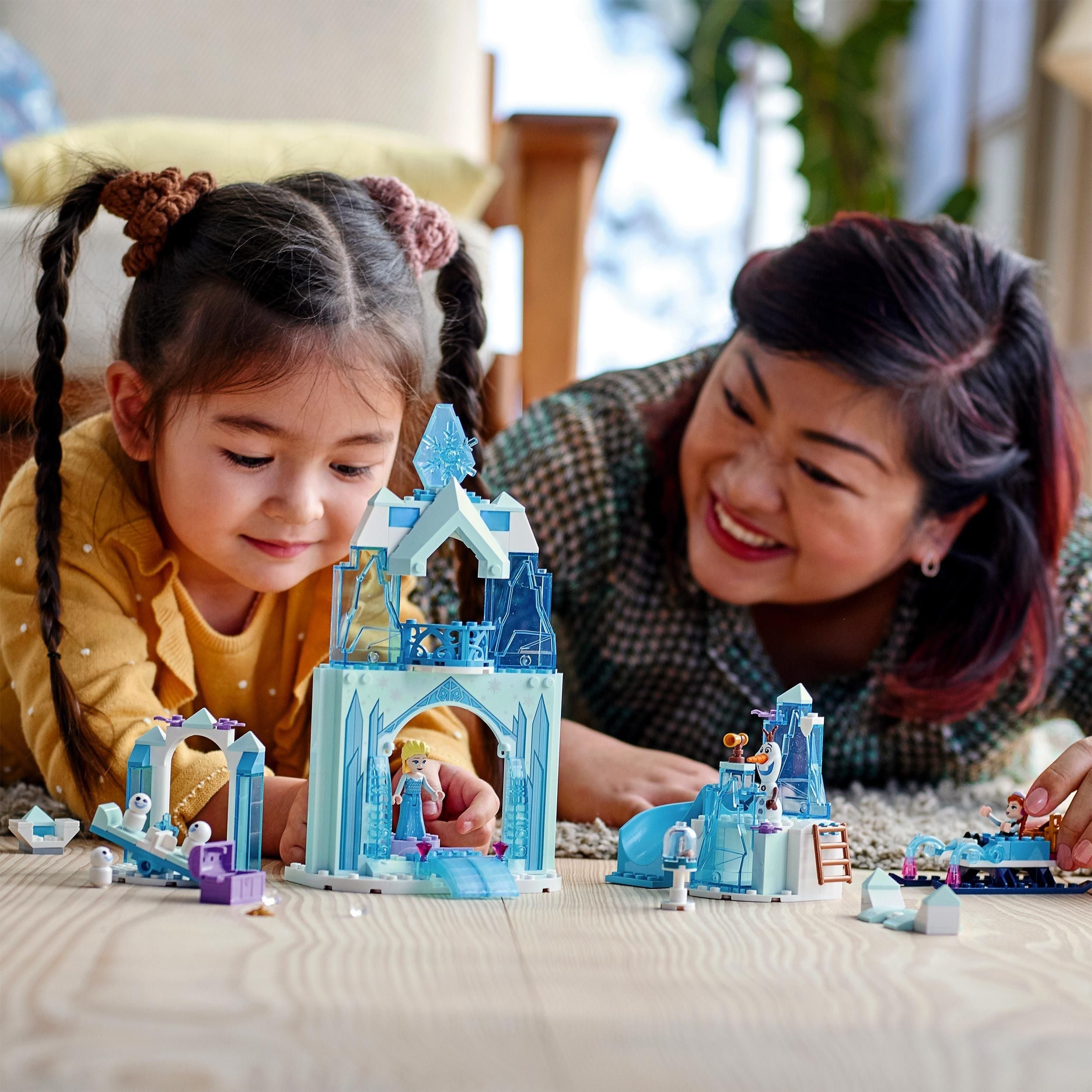 Child and adult playing with LEGO® Disney Anna and Elsa’s Frozen Wonderland set featuring an ice castle and mini-doll figures.