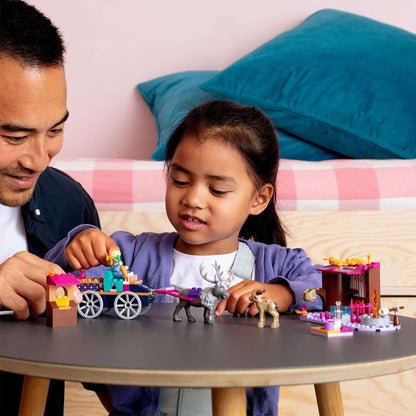 Father and daughter enjoying LEGO Disney Frozen 2 Elsa's Wagon Adventure set, featuring colorful bricks and characters.