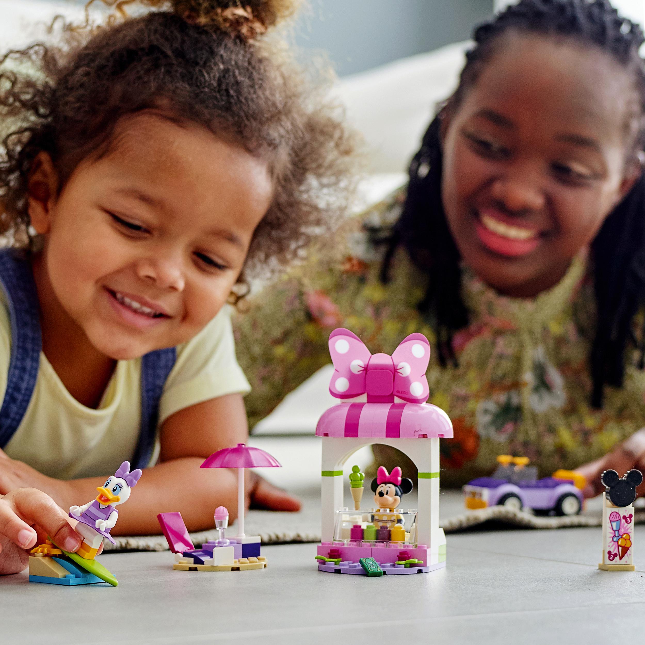 Child and adult enjoying building LEGO Disney Mickey Mouse Minnie Ice Cream Shop, featuring colorful minifigures and accessories.