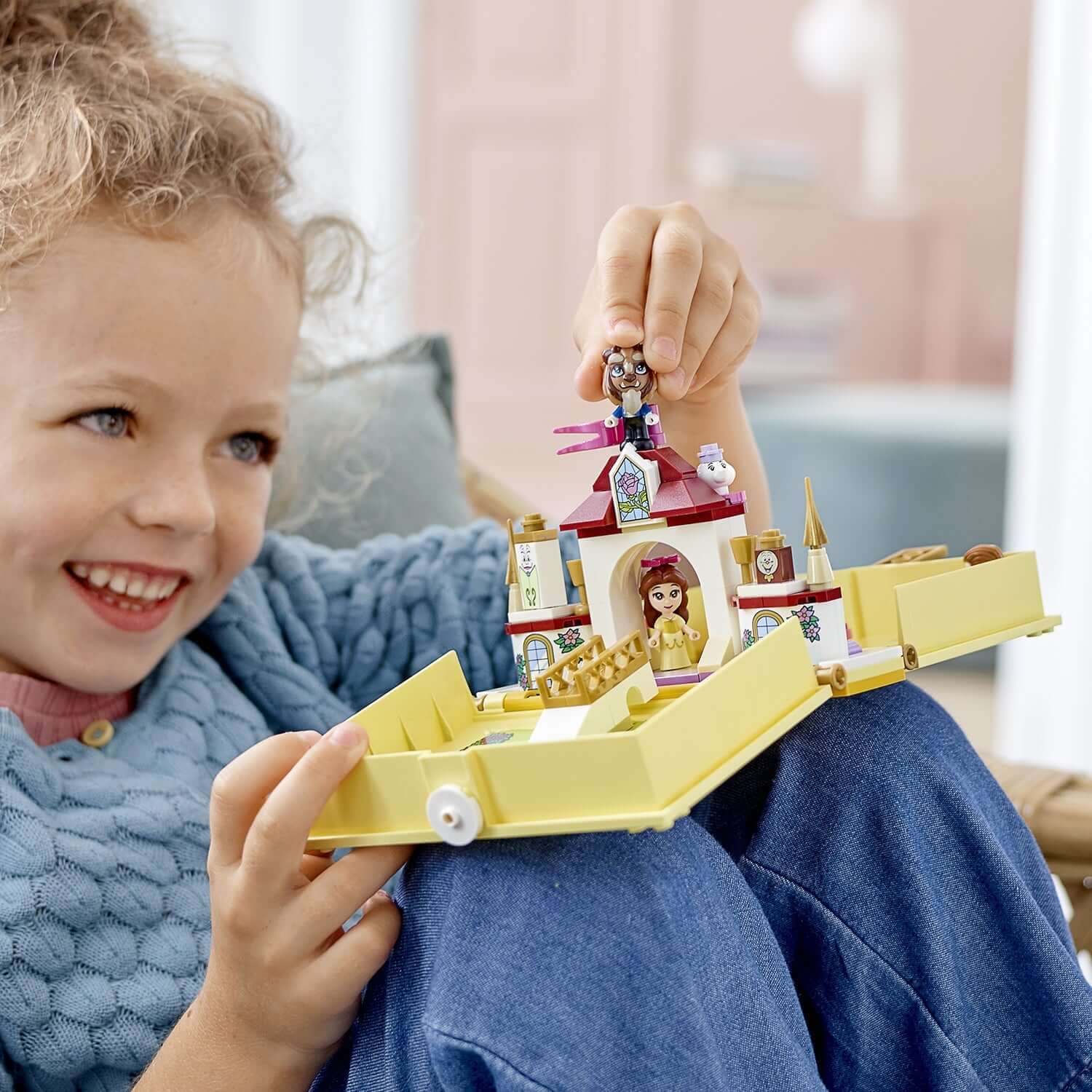 Child joyfully playing with LEGO Disney Princess Belle's Storybook Set 43177, showcasing Belle and Beast figures.
