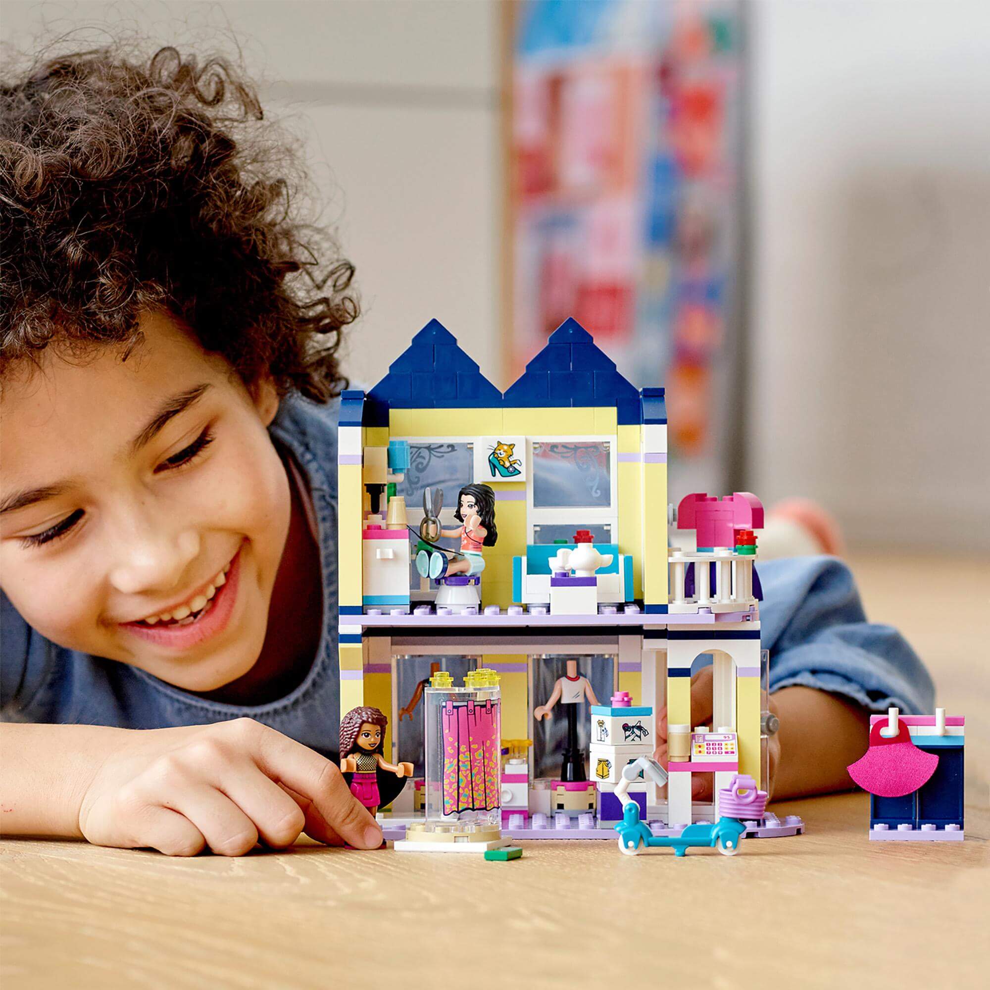 Child playing with LEGO® Friends Emma's Fashion Shop Play Set 41427, showcasing imaginative scenes from the TV show.