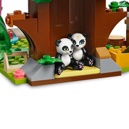Two cute panda figurines sitting in a LEGO® Friends Panda Jungle Tree House set, surrounded by vibrant jungle elements.
