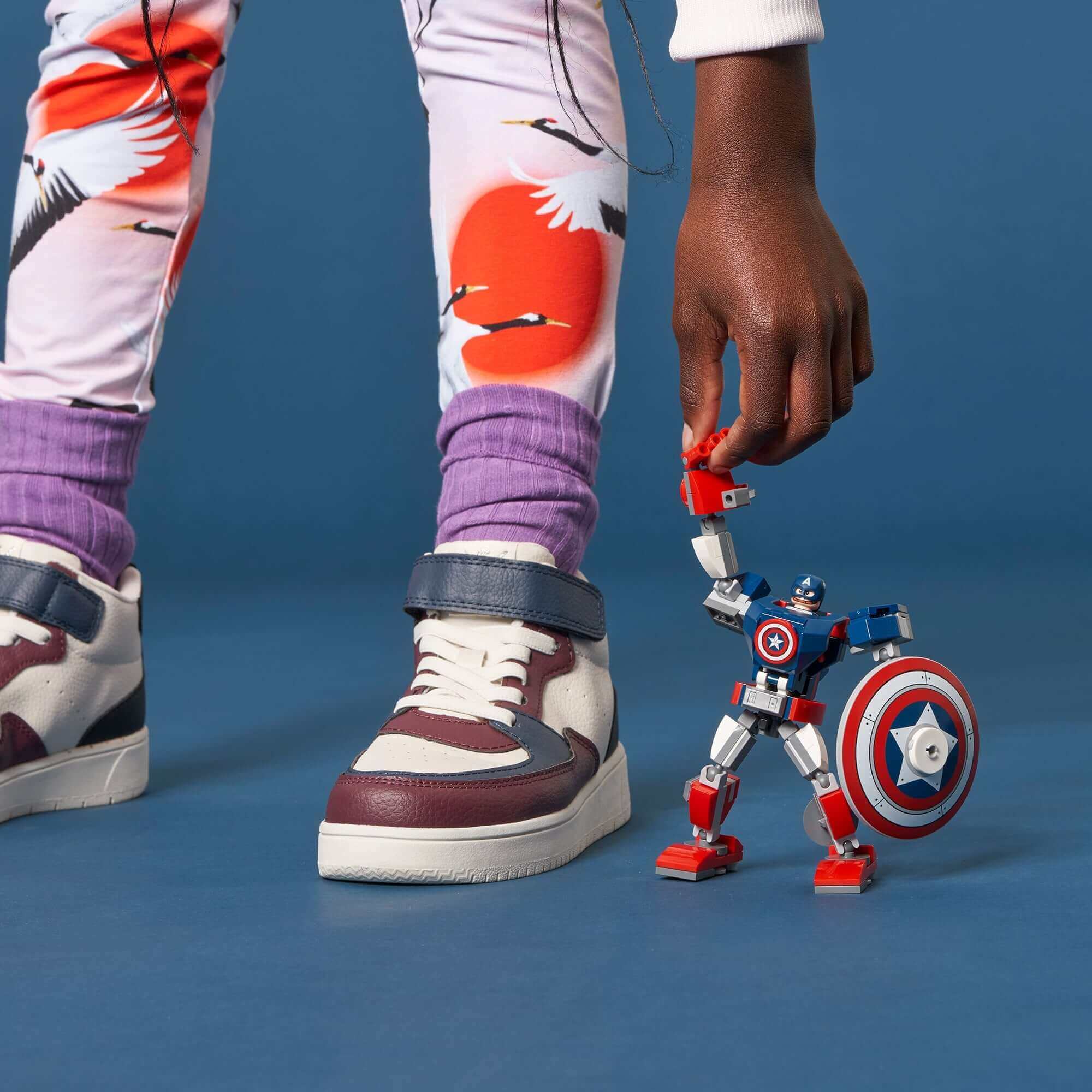 Child playing with LEGO Marvel Avengers Captain America mech toy, featuring movable limbs and detachable shield.