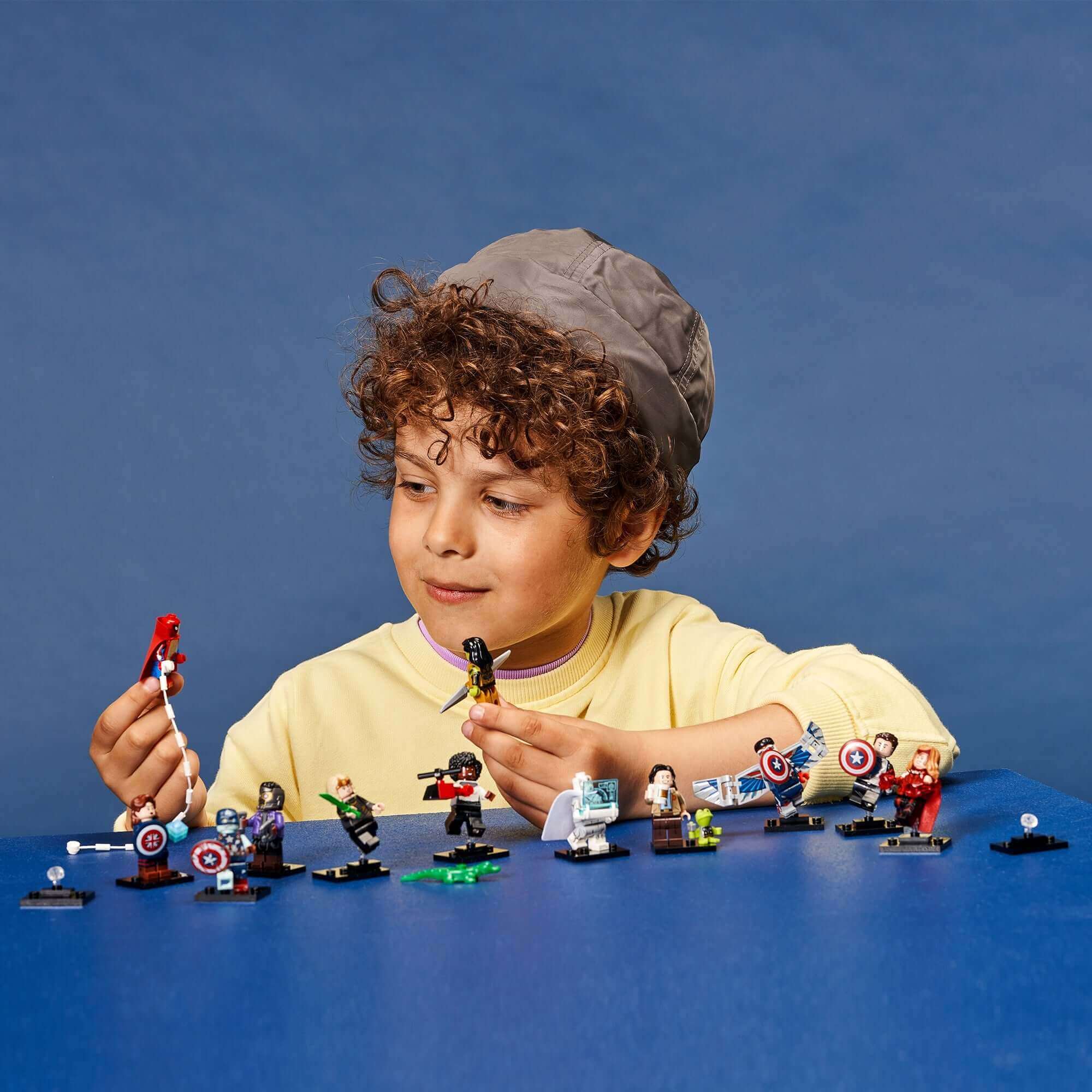 Child exploring LEGO® Minifigures from Marvel Studios Building Set 71031 with various accessories and characters.