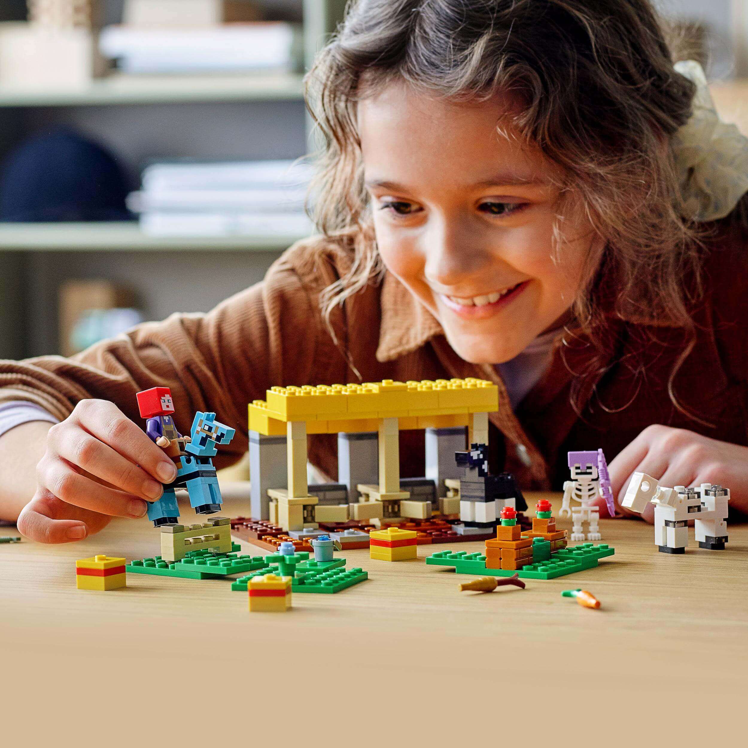 Child playing with LEGO® Minecraft The Horse Stable Farm Toy 21171, creating fun scenes with figures and accessories.