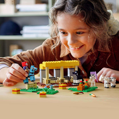 Child playing with LEGO® Minecraft The Horse Stable Farm Toy 21171, creating fun scenes with figures and accessories.