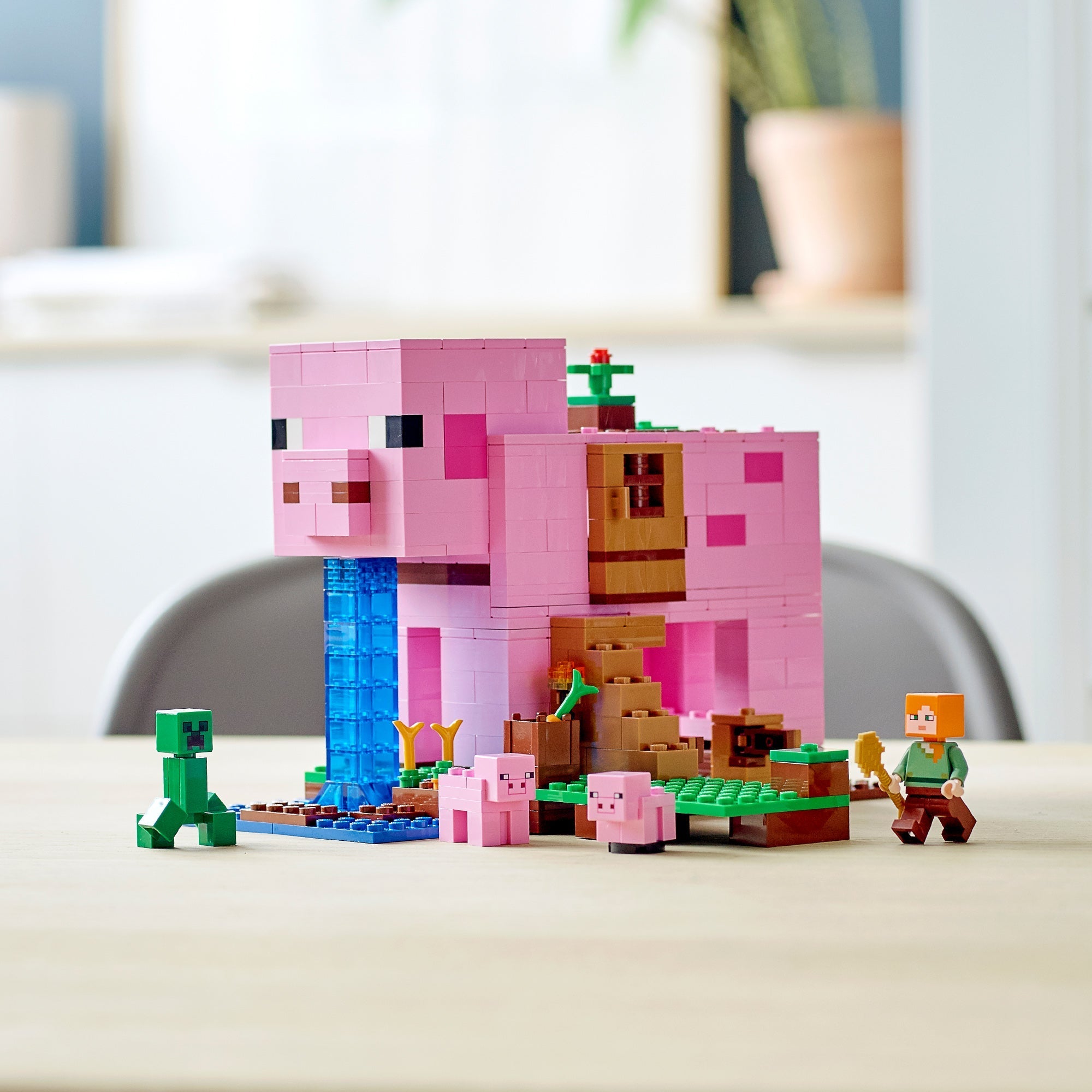 LEGO Minecraft Pig House 21170 with characters Steve, Creeper, and baby pigs set in a cozy indoor scene.
