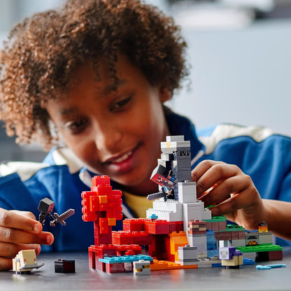 Child building with LEGO® Minecraft The Ruined Portal set 21172, creating a vibrant, imaginative landscape.