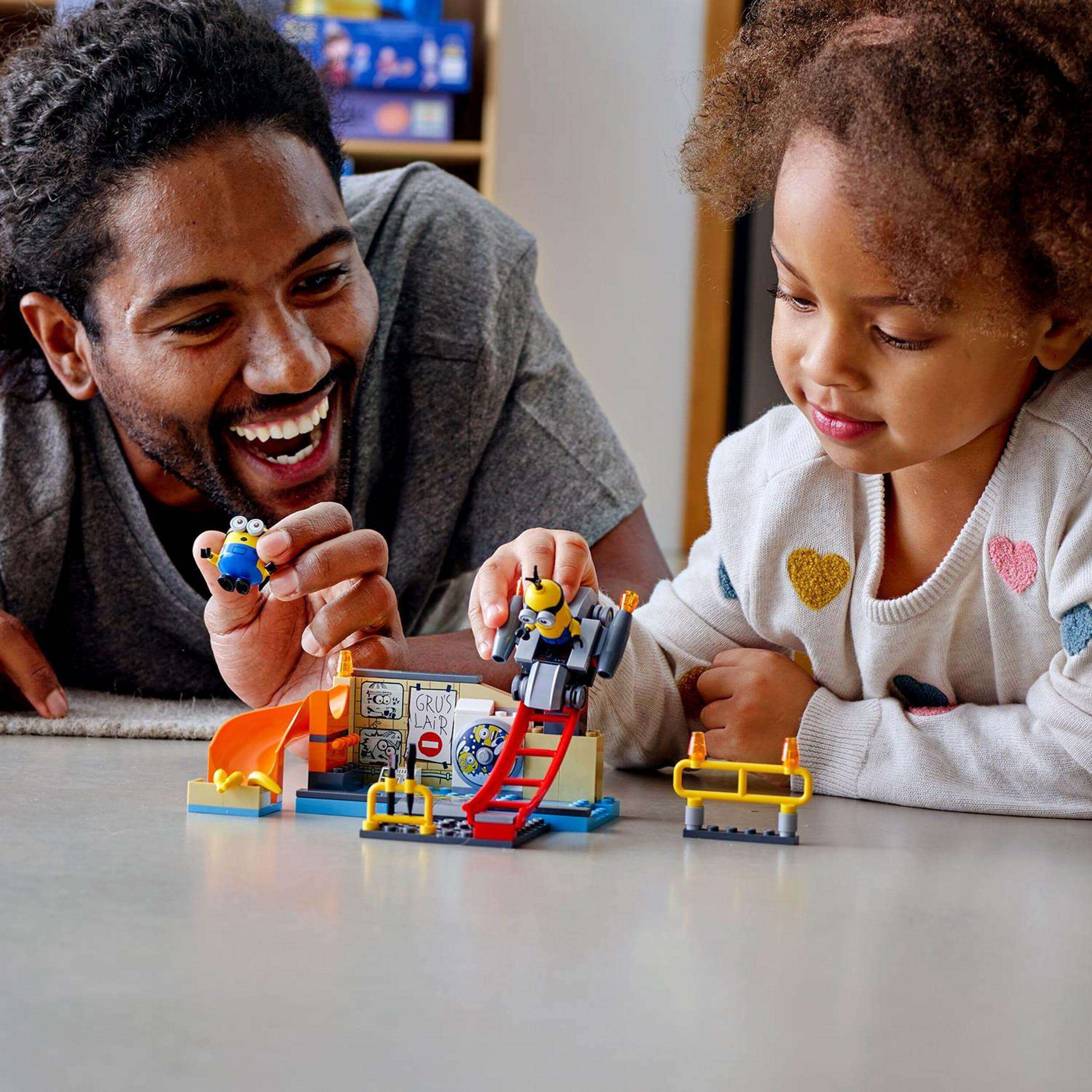 A father and daughter joyfully playing with the LEGO® Minions in Gru’s Lab set, featuring vibrant figures and creative elements.