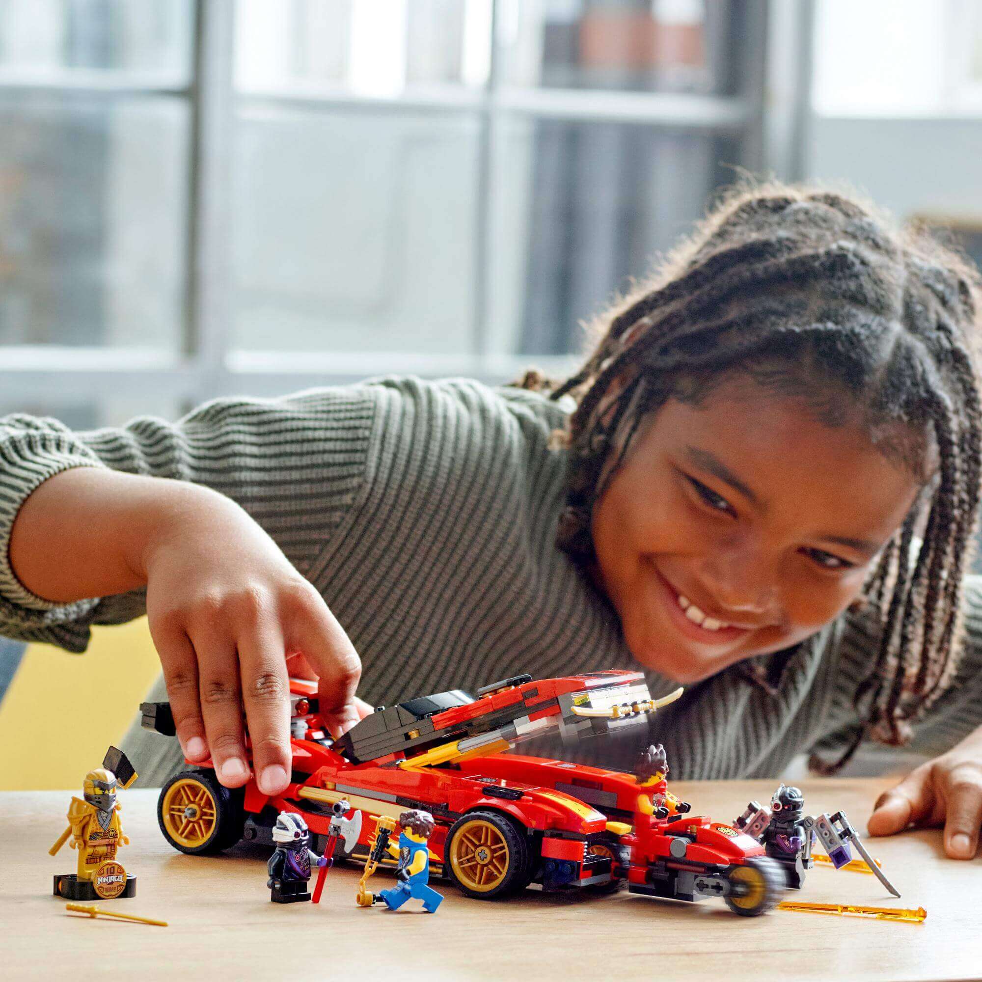 Child playing with LEGO NINJAGO Legacy X-1 Ninja Charger set, featuring a toy car and ninjas, for imaginative roleplay.