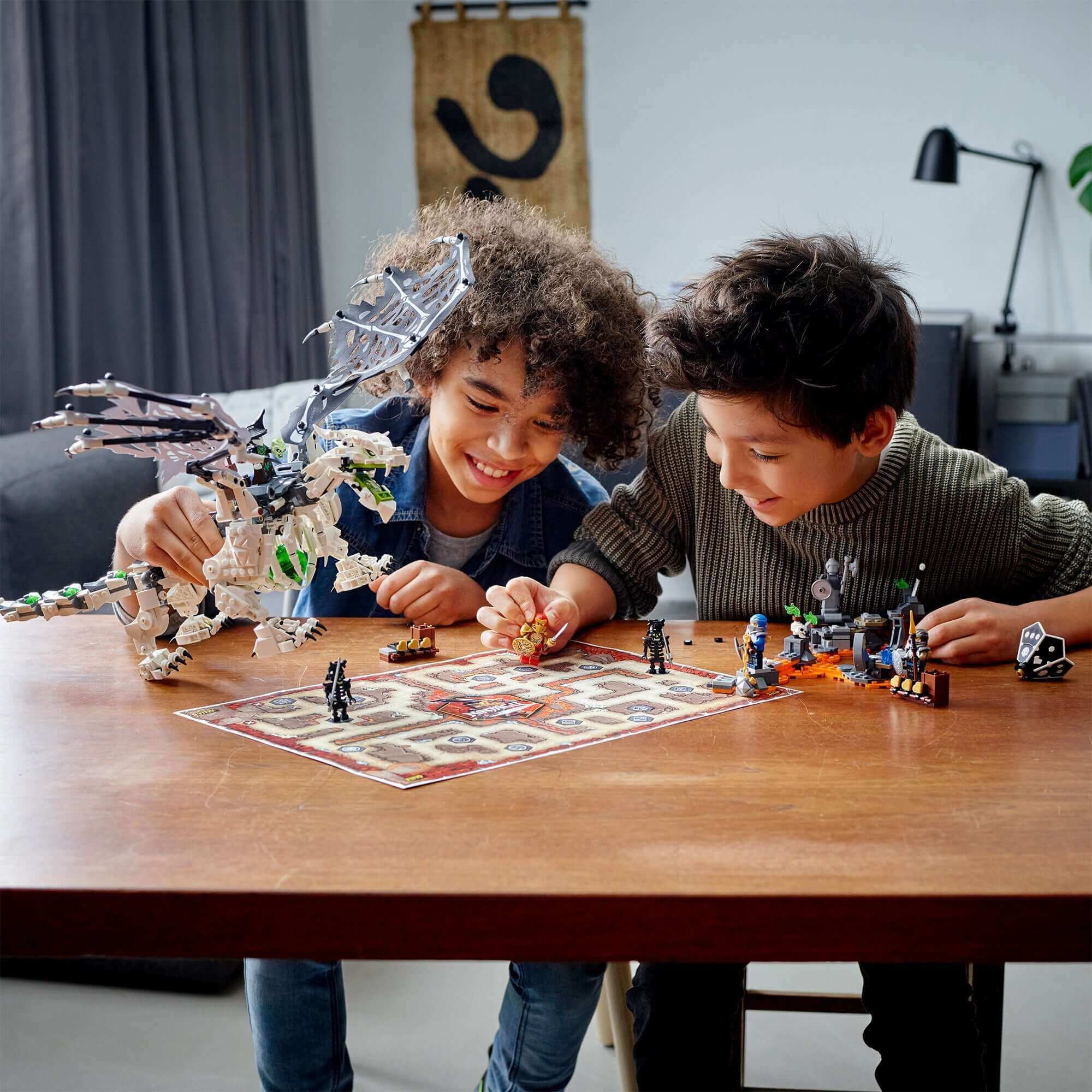 Two kids playing with LEGO® NINJAGO Skull Sorcerer's Dragon toy set on a table, featuring heroes and a dragon.