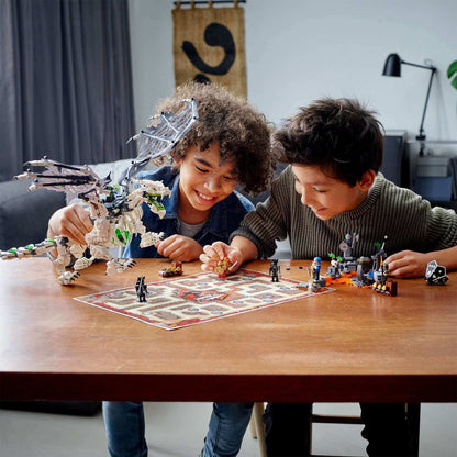 Two kids playing with LEGO® NINJAGO Skull Sorcerer's Dragon toy set on a table, featuring heroes and a dragon.