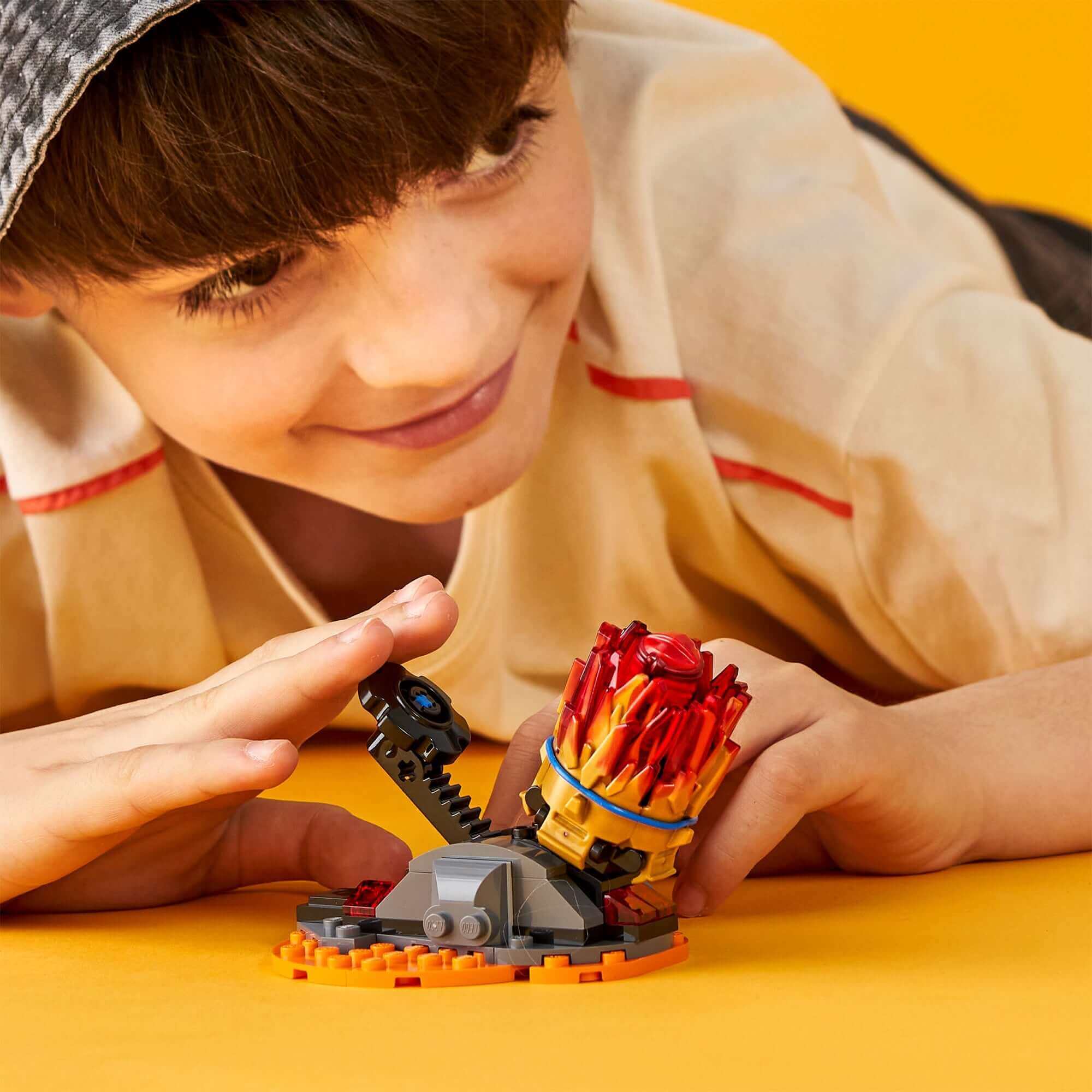 Child playing with LEGO® NINJAGO Spinjitzu Burst Kai spinner toy 70686, creating adventures and excitement.