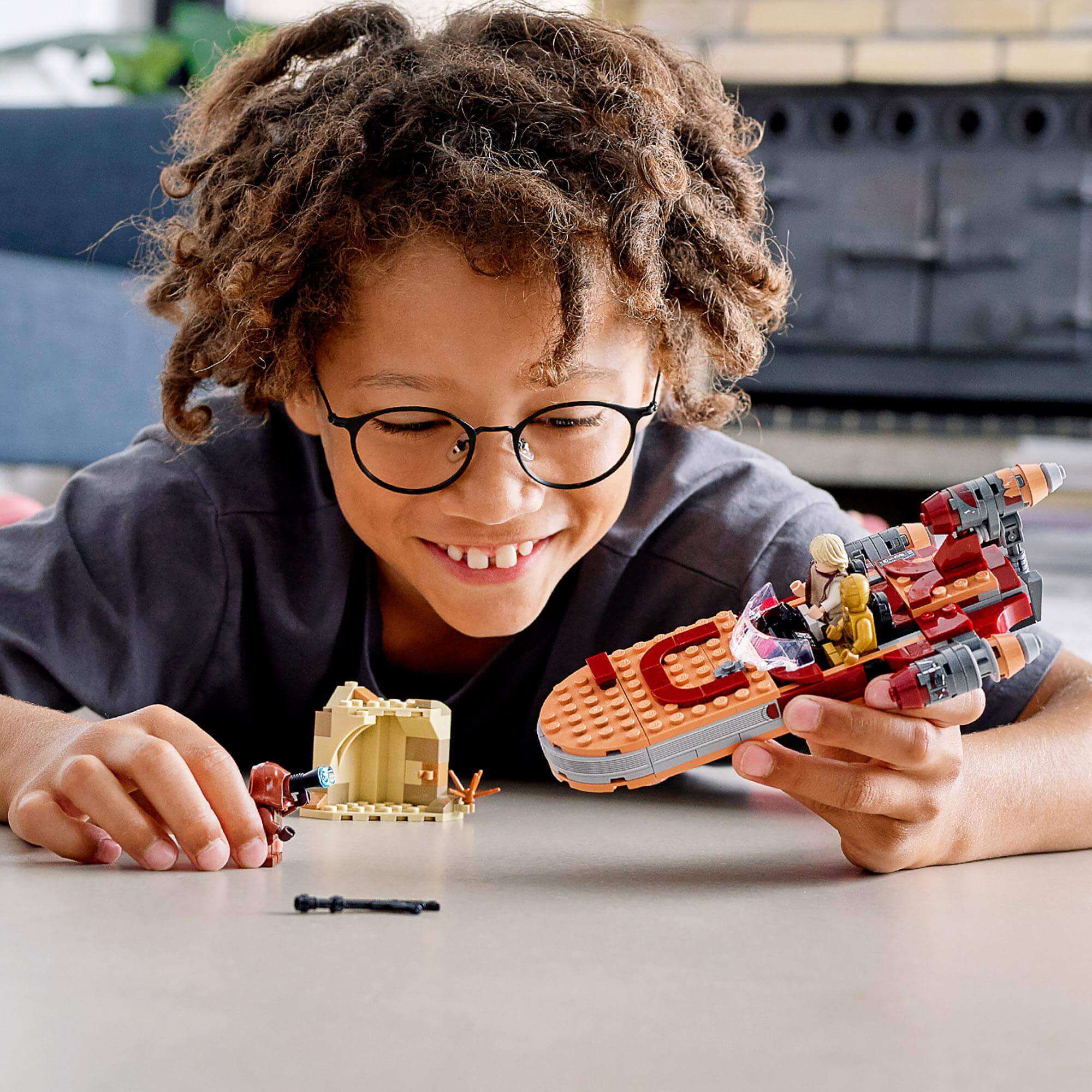 Child playing with LEGO® Star Wars Luke Skywalker landspeeder set, enjoying a fun and imaginative build.