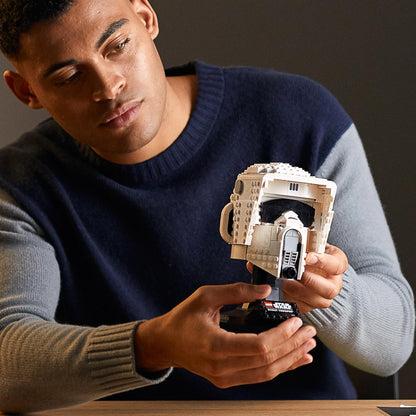 Man holding a detailed LEGO® Star Wars Scout Trooper Helmet model, showcasing adult collectibles.