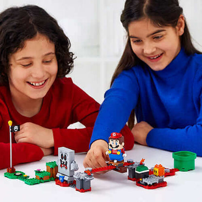 Two children enjoying the LEGO® Super Mario™ Whomp's Lava Trouble Expansion Set 71364, playing with Mario figure.