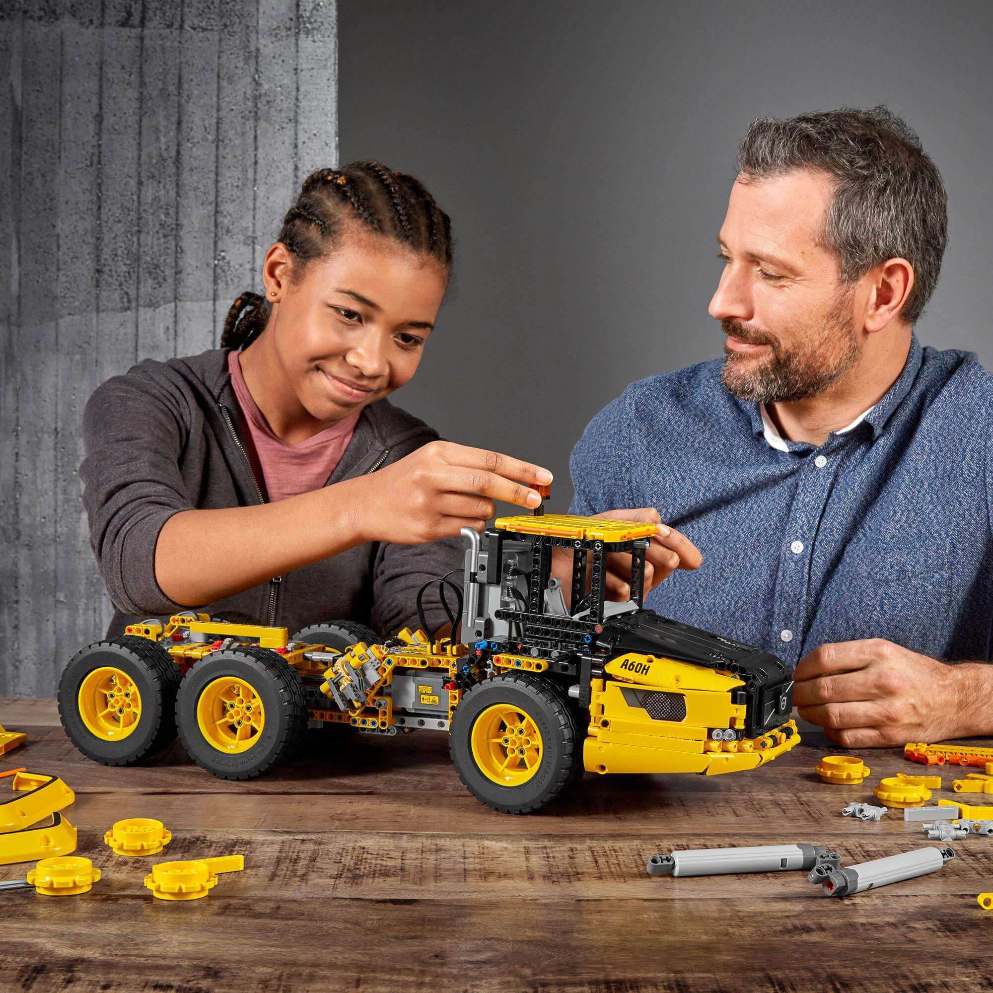 Child and adult assembling LEGO® Technic 6x6 Volvo Articulated Hauler truck, showcasing fun construction playtime.