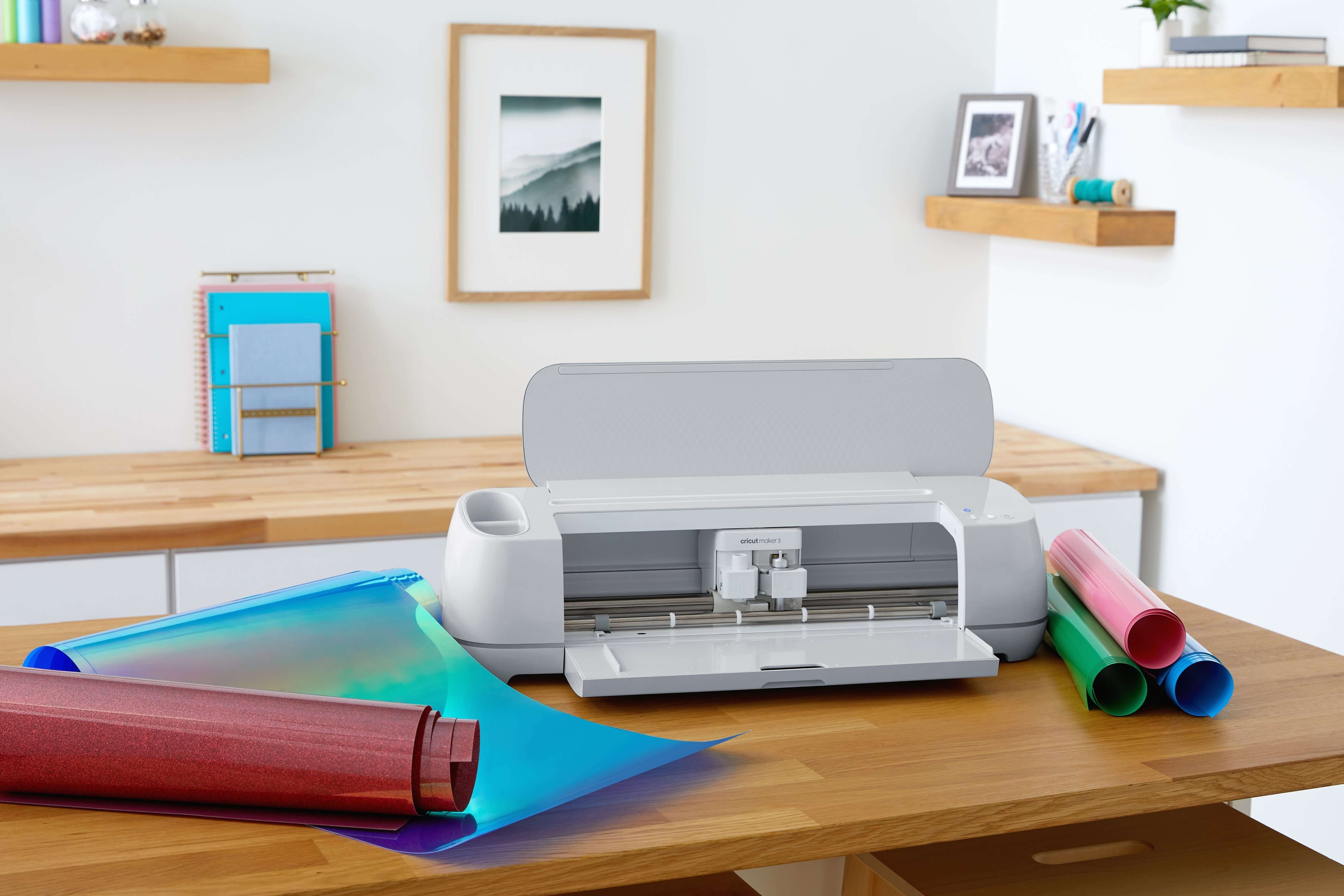 Cricut Maker 3 positioned on a wooden table with colorful Smart Materials and crafting tools for creative projects.