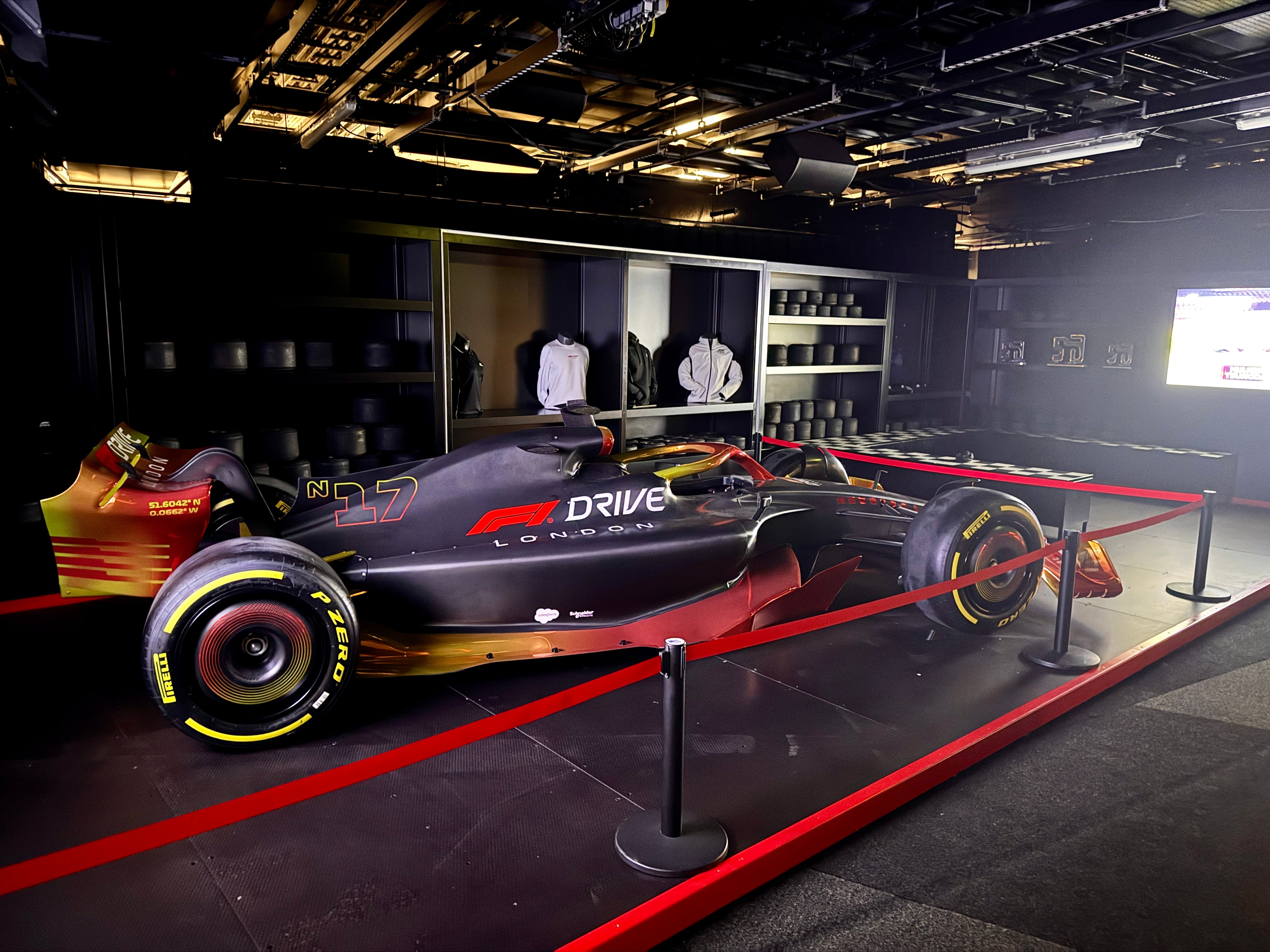F1 racing car on display with red barriers, showcasing advanced design and sponsor branding in an exhibition space.
