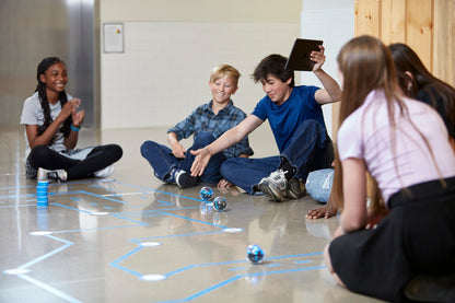 Students engaging in hands-on coding activities with Sphero BOLT+ robots on a floor interface at school.