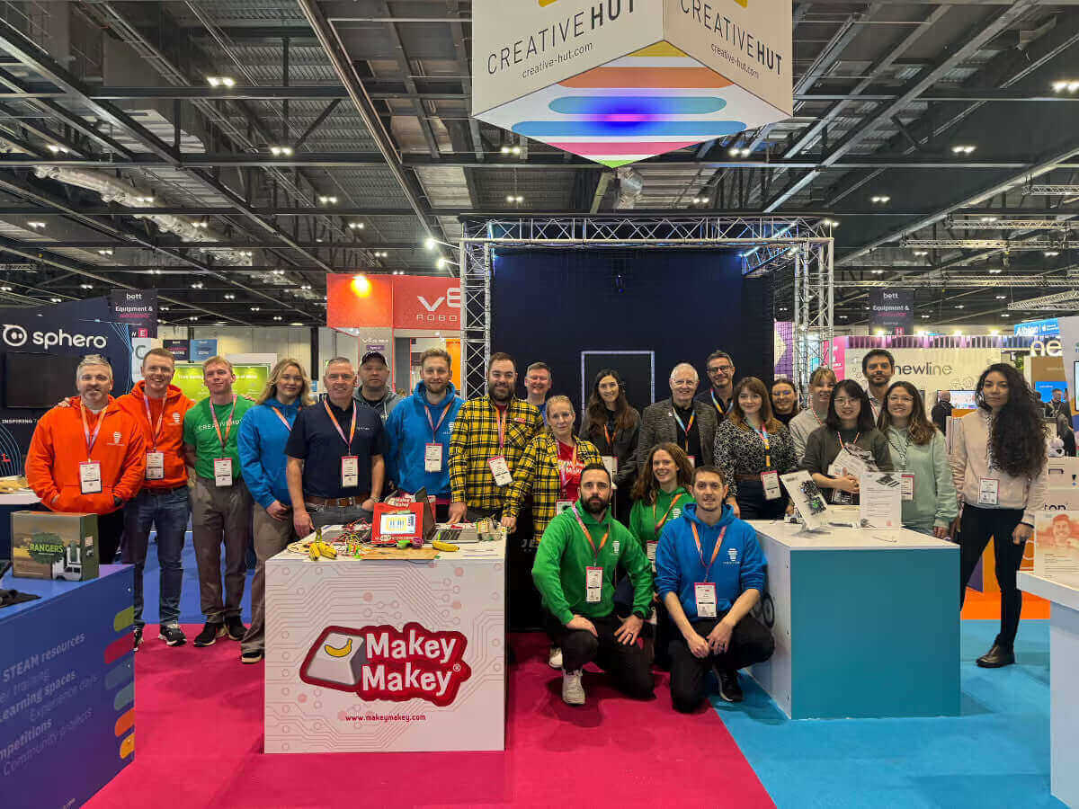 Group photo at Creative Hut booth showcasing innovative educational tools like Makey Makey at an exhibition.
