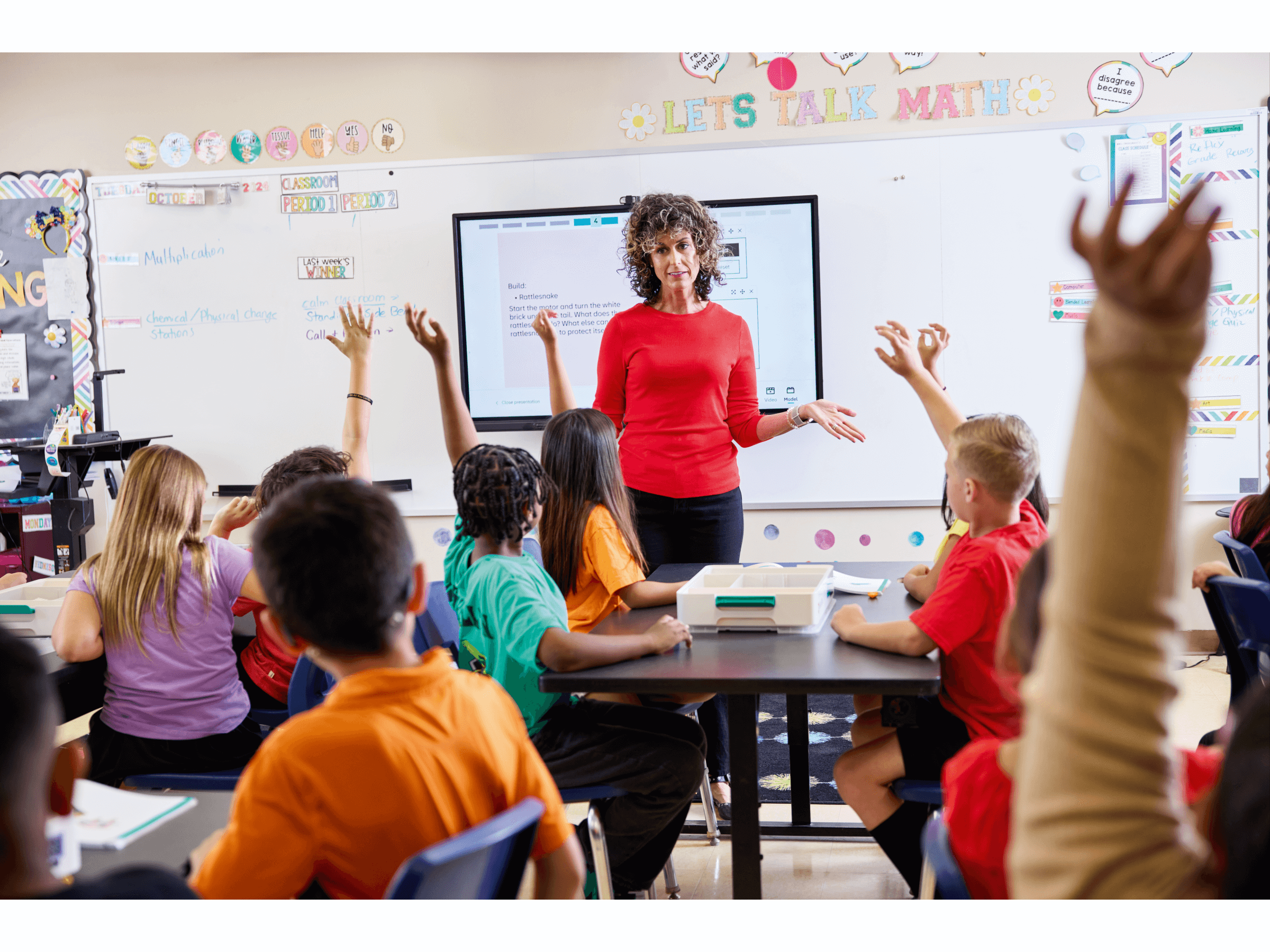 Teacher engaging students in a classroom discussion about math, children raising hands to participate.