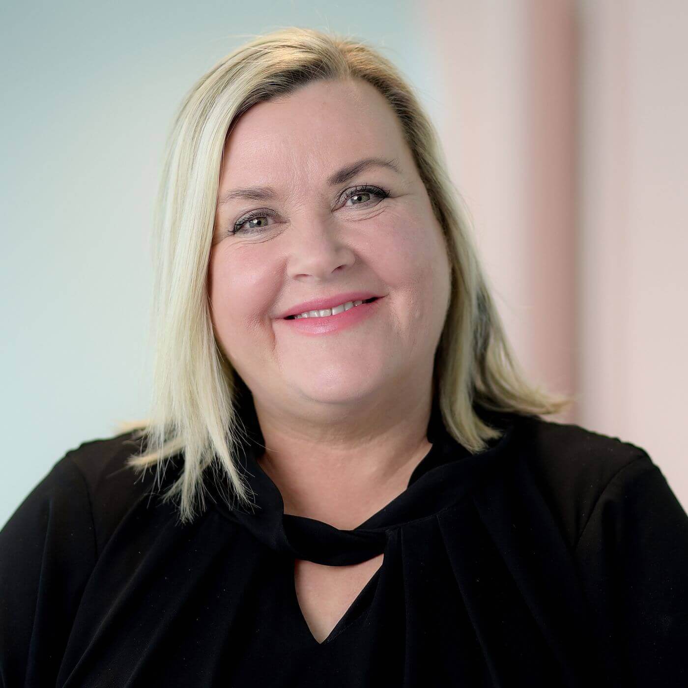 Smiling woman in a black top, showcasing a friendly expression and professional appearance.