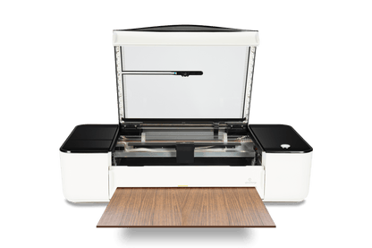Glowforge Pro laser printer with open lid and wood material, ideal for large-scale projects and nonstop printing.