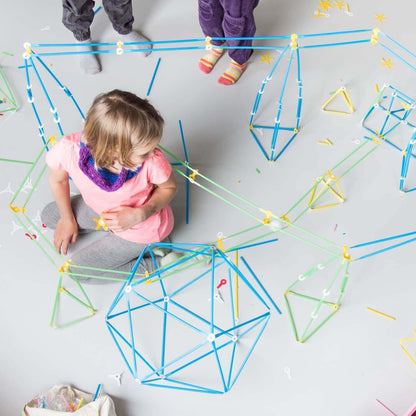 Children building creative structures with colorful straws from the Imagination Kit on a floor.