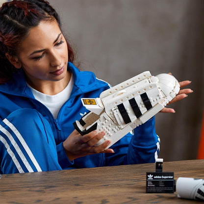 Person holding LEGO® adidas Originals Superstar Set 10282, showcasing the iconic trainer design.