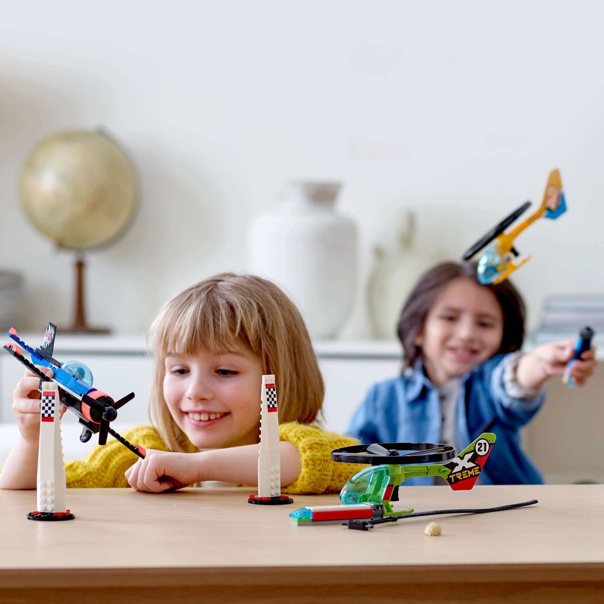 Kids playing with LEGO® City Airport Air Race set, featuring toy helicopters and stunt planes for imaginative fun.