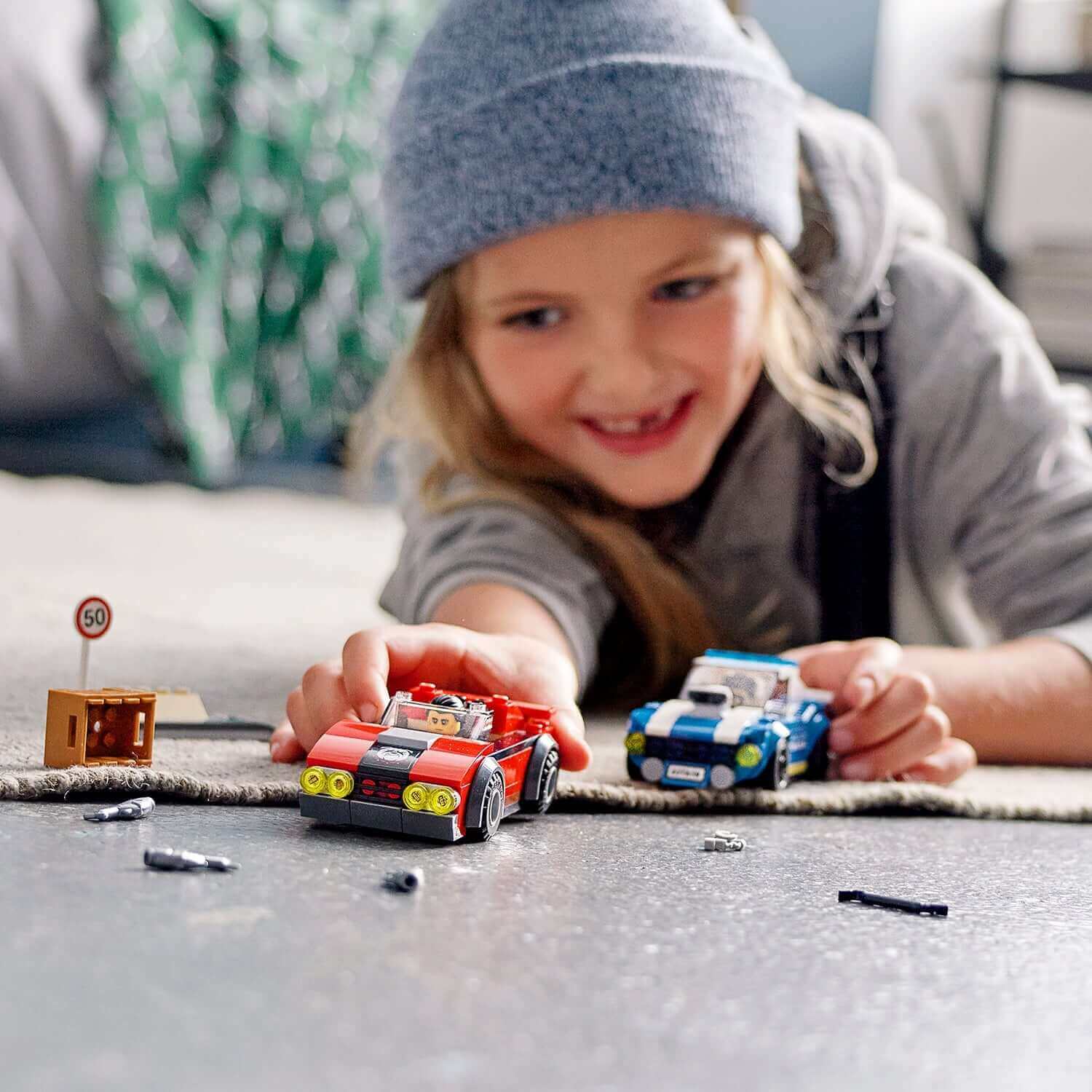 Child playing with LEGO® City Police Highway Arrest Set 60242, featuring racing cars and fun accessories.