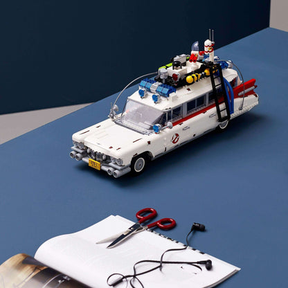 LEGO® Creator Expert Ghostbusters ECTO-1 Set 10274 model on a table with scissors and a notebook, perfect for fans.